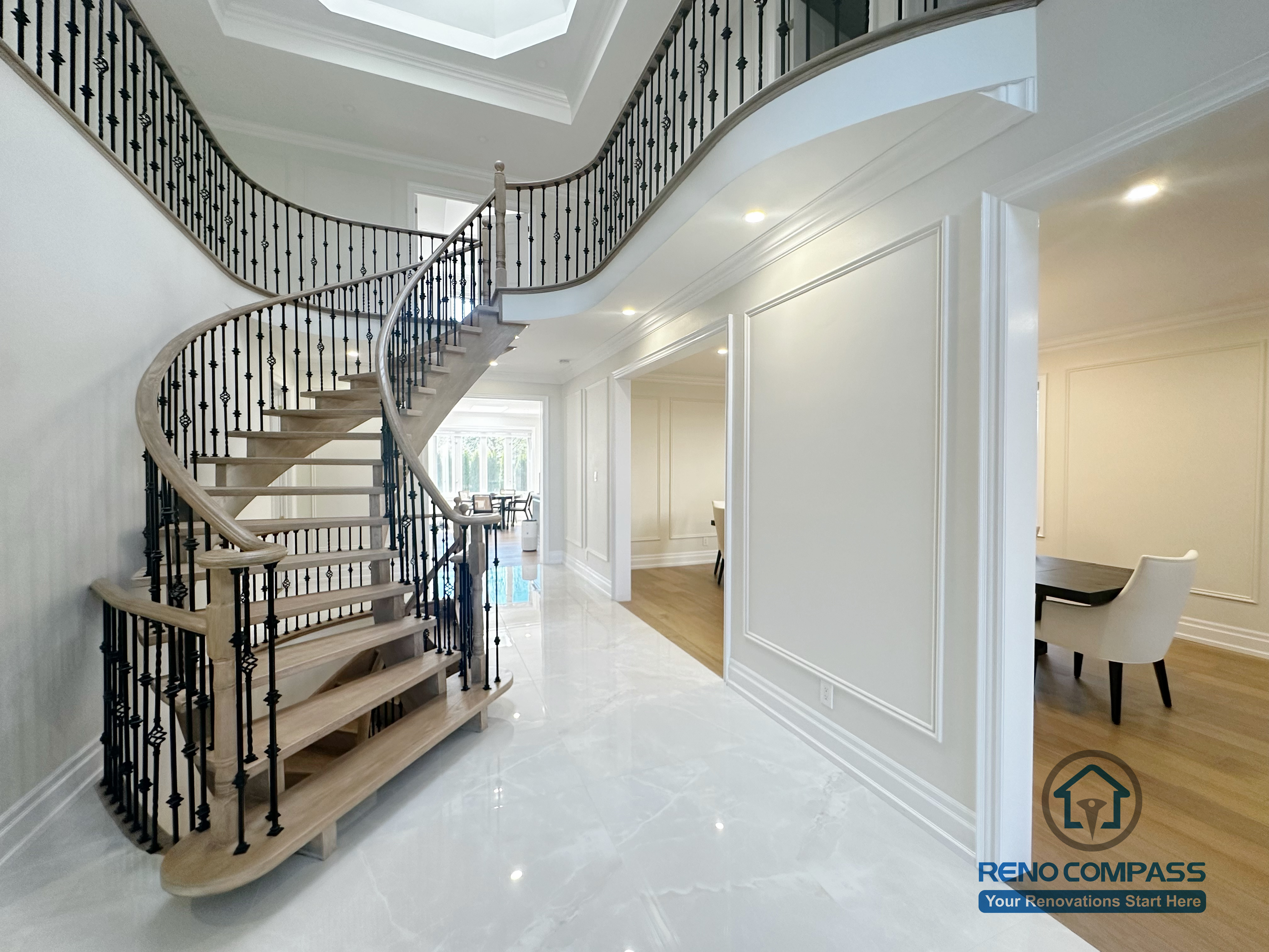 This image showcases the front view of a grand curved staircase as part of a North York flooring and stair renovation. The staircase features solid hardwood treads, smooth curved stringers, and decorative iron balusters, forming a strong architectural focal point at the home’s entrance. The surrounding flooring is finished with polished, light-toned surfaces that enhance brightness and reflect natural light. This renovation highlights precise craftsmanship and seamless coordination between flooring and stair design, creating an elegant and cohesive interior for North York homes.