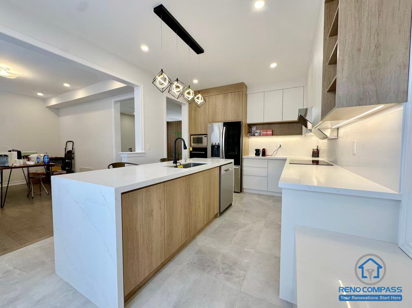This Stouffville interior renovation presents a full view of an open-concept kitchen featuring a custom wood-finished island, quartz countertops, and integrated appliances. Modern pendant lighting, recessed ceiling lights, and seamless cabinetry create a spacious and functional layout that connects the kitchen with adjacent living areas. Completed by a professional Toronto renovation company, Reno Compass Inc., this project demonstrates thoughtful space planning and high-quality interior renovation craftsmanship.