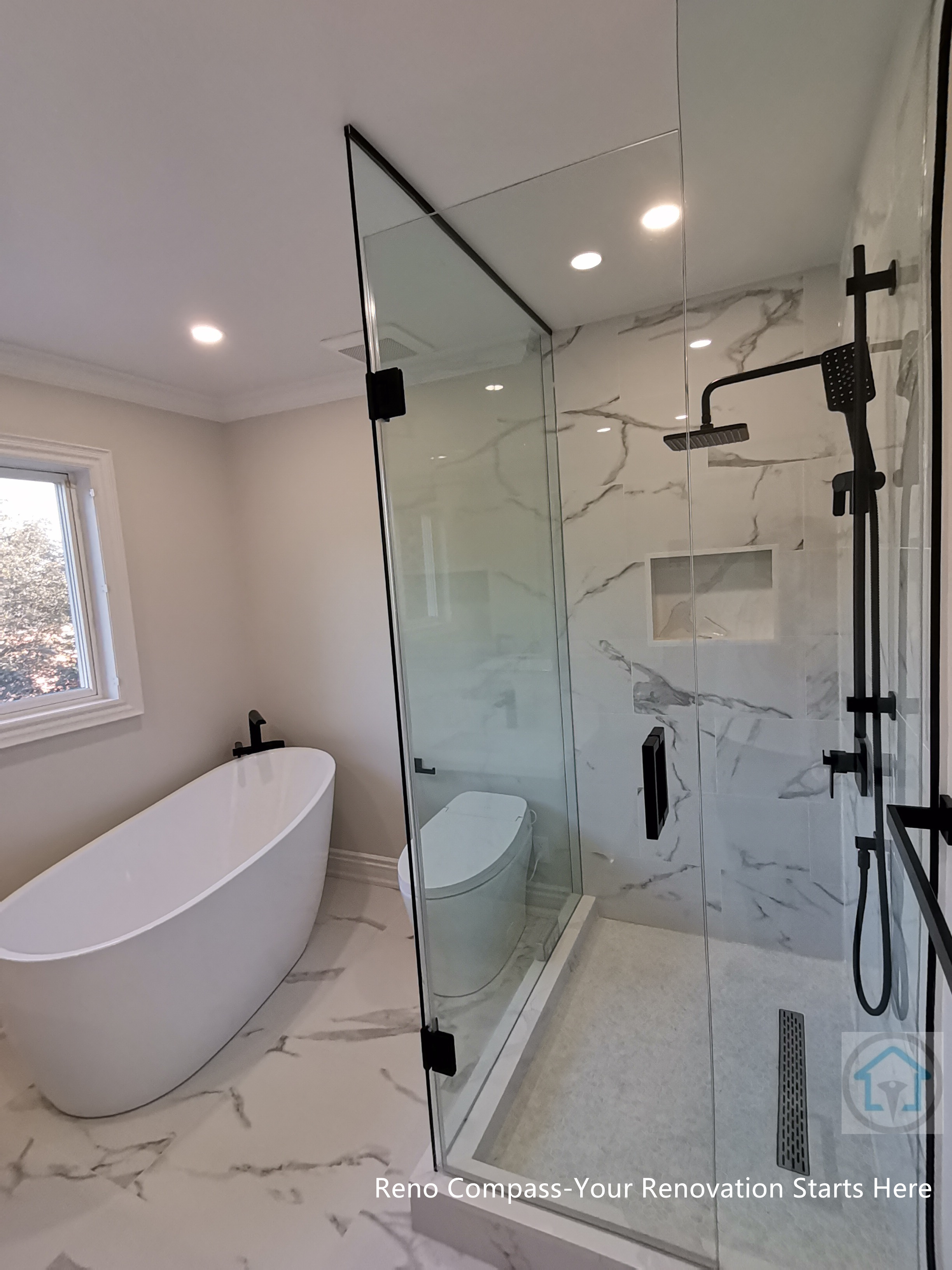 This Thornhill bathroom renovation features a glass-enclosed shower with marble-style wall tiles, modern black fixtures, and a built-in niche for storage. The clean layout integrates the shower area seamlessly with the rest of the bathroom, creating a bright, functional, and well-balanced space for everyday use.