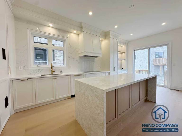 Bright open concept kitchen in Toronto featuring a large island, natural light, and clean cabinetry layout, designed for modern living and improved space flow.
