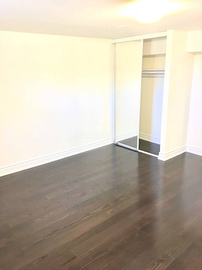 This Toronto basement renovation features a newly finished bedroom with rich hardwood flooring, fresh neutral walls, and a built-in closet with sliding doors. The clean layout and warm lighting create a comfortable and functional living space ideal for rental or family use. Completed by a professional Toronto renovation company, this basement bedroom upgrade enhances both property value and everyday living comfort.
