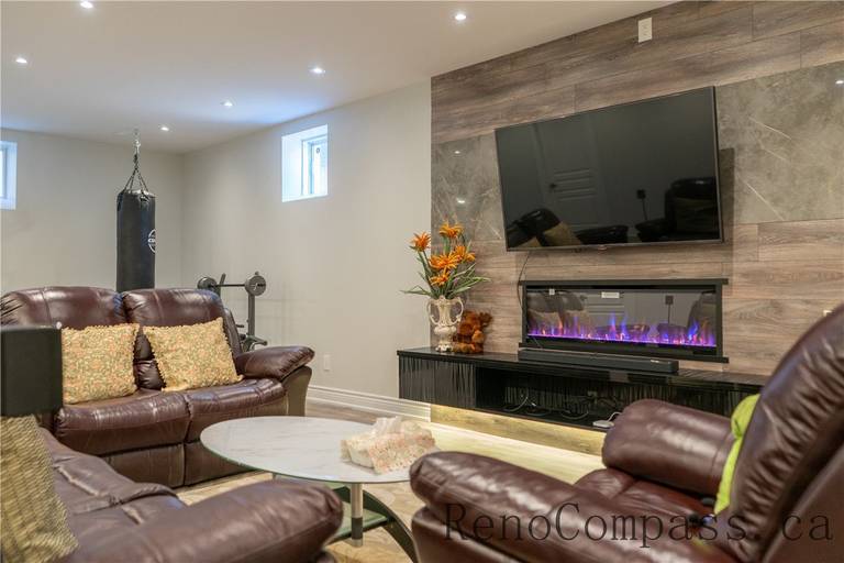 This Richmond Hill basement renovation features a modern living room with custom TV feature wall, built-in electric fireplace, upgraded flooring, and recessed lighting. Designed for comfort and entertainment, the warm and functional layout highlights the craftsmanship of a trusted Toronto renovation company specializing in full house and basement renovations.