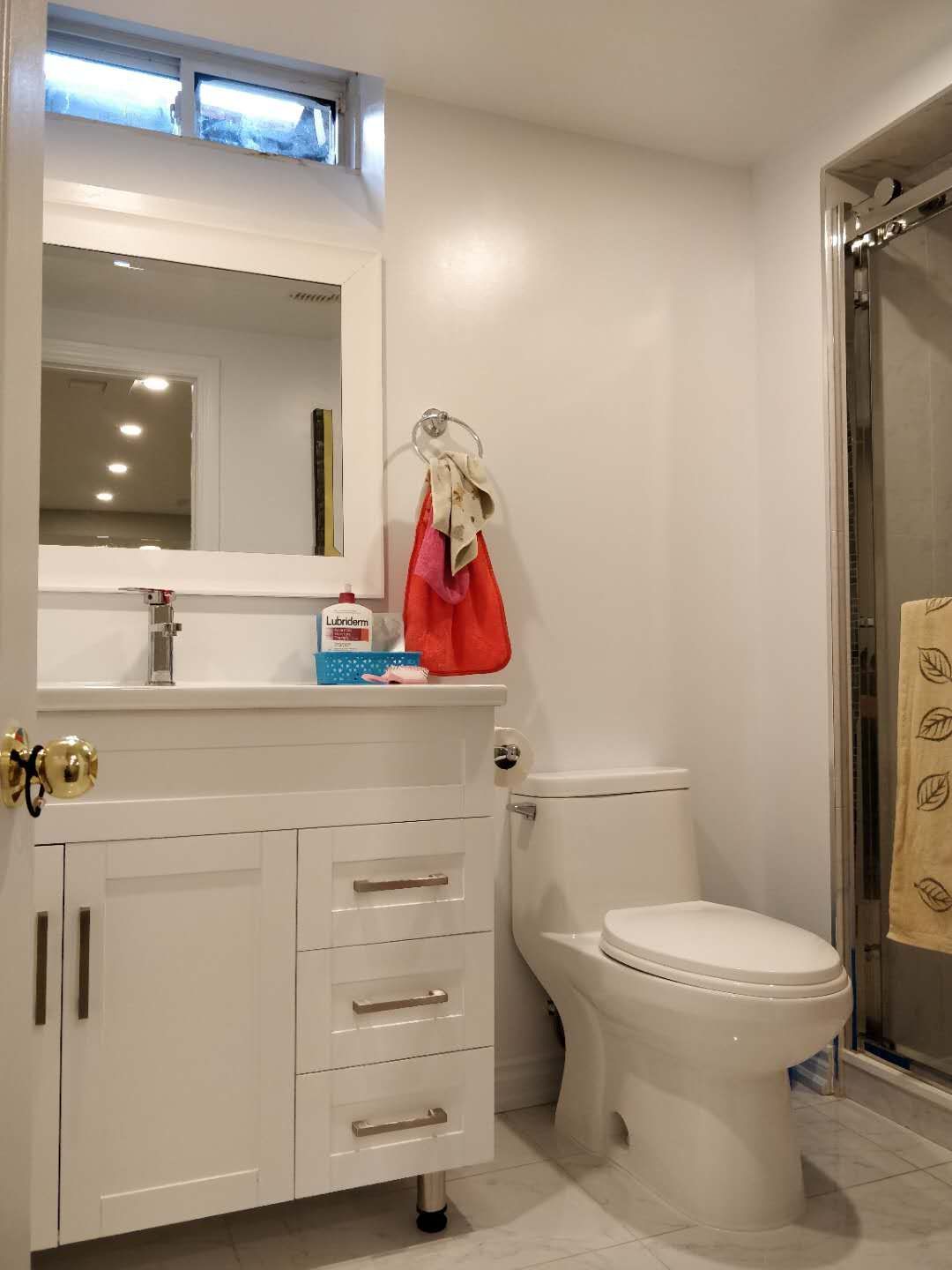 This Scarborough basement renovation includes a newly built bathroom featuring a clean white vanity cabinet, modern sink, toilet, and glass shower enclosure. The bright lighting and neutral finishes create a fresh and functional bathroom space, adding comfort and value to the basement living area by a professional Toronto renovation company.