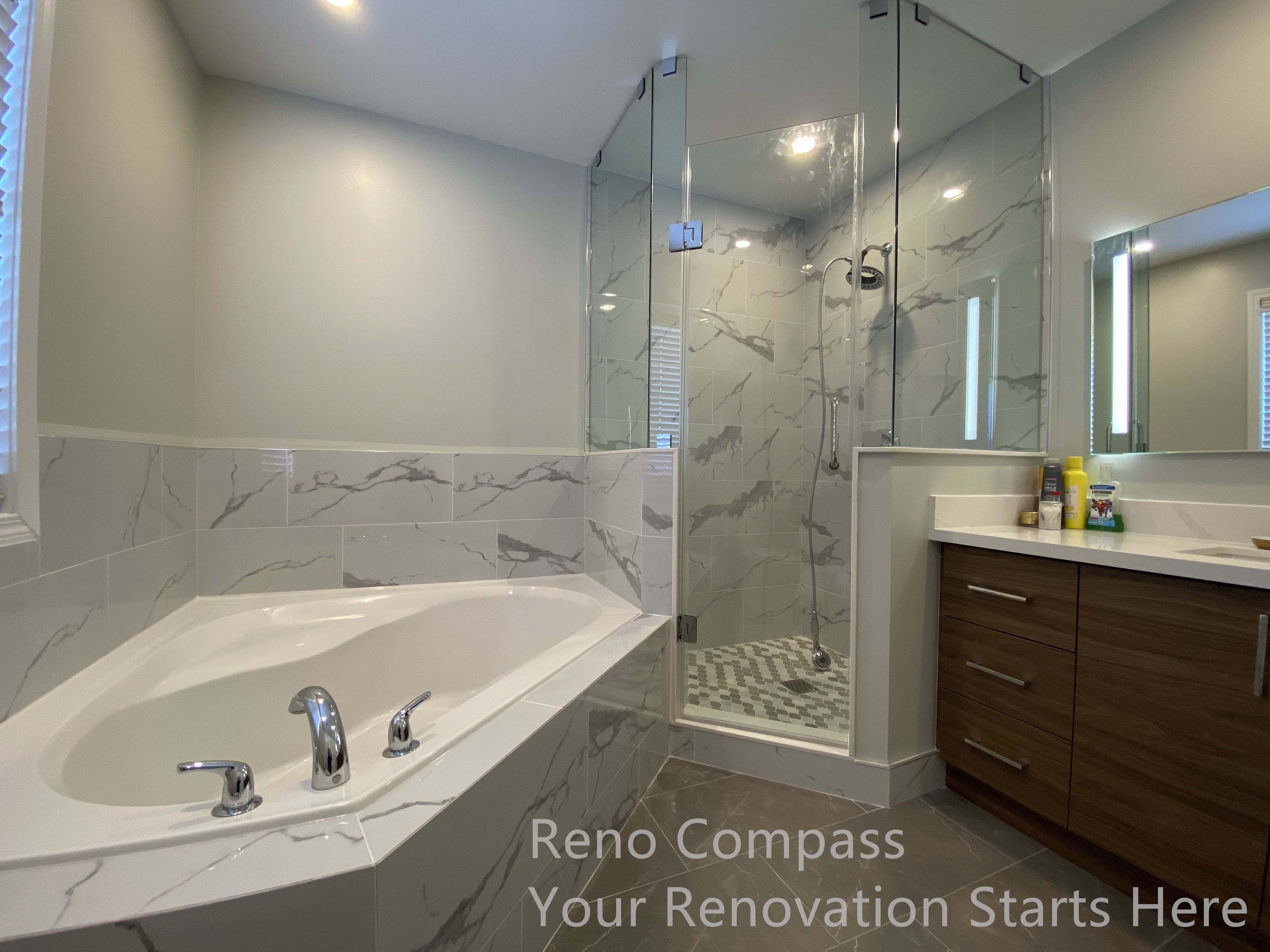 This Newmarket bathroom renovation features a well-coordinated layout combining a built-in bathtub, a frameless glass shower enclosure, and a modern vanity with clean-lined storage. Marble-look wall tiles extend around the tub and shower area, creating a seamless visual connection while enhancing durability and moisture resistance. The transparent glass shower enclosure preserves openness and allows light to circulate throughout the space, making the bathroom feel brighter and more spacious. Neutral finishes and carefully selected fixtures contribute to a calm, spa-inspired atmosphere designed for everyday comfort and long-term use. This renovation was completed by Reno Compass, serving homeowners in Newmarket and across the GTA.