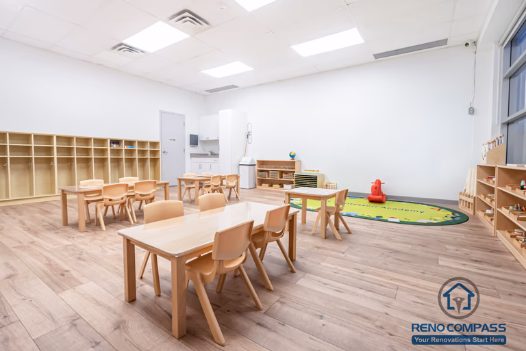 This Markham daycare renovation showcases a spacious classroom learning area designed to support group activities, early education, and daily routines. Child-sized tables and chairs are arranged to encourage collaboration while maintaining clear circulation for supervision. Open shelving and low-height cubbies provide organized storage that promotes independence and easy access for children. Durable, slip-resistant flooring and bright overhead lighting ensure safety, comfort, and long-term usability. Completed by a Toronto renovation company, Reno Compass Inc., this daycare interior renovation reflects a thoughtful balance of educational functionality, safety compliance, and efficient space planning for modern childcare environments.