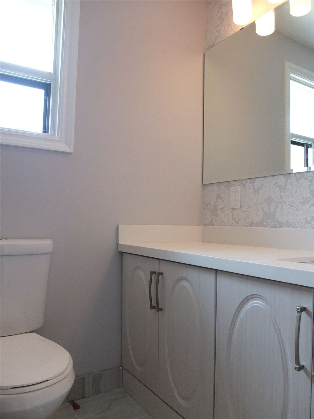 This bathroom renovation in North York features a modern vanity with a quartz countertop, under-mount sink, brushed nickel faucet, and framed mirror with warm wall lighting. The updated design improves both functionality and visual comfort, creating a clean and elegant bathroom space. Completed by a professional Toronto renovation team, the project focuses on quality finishes, practical storage, and timeless interior style.