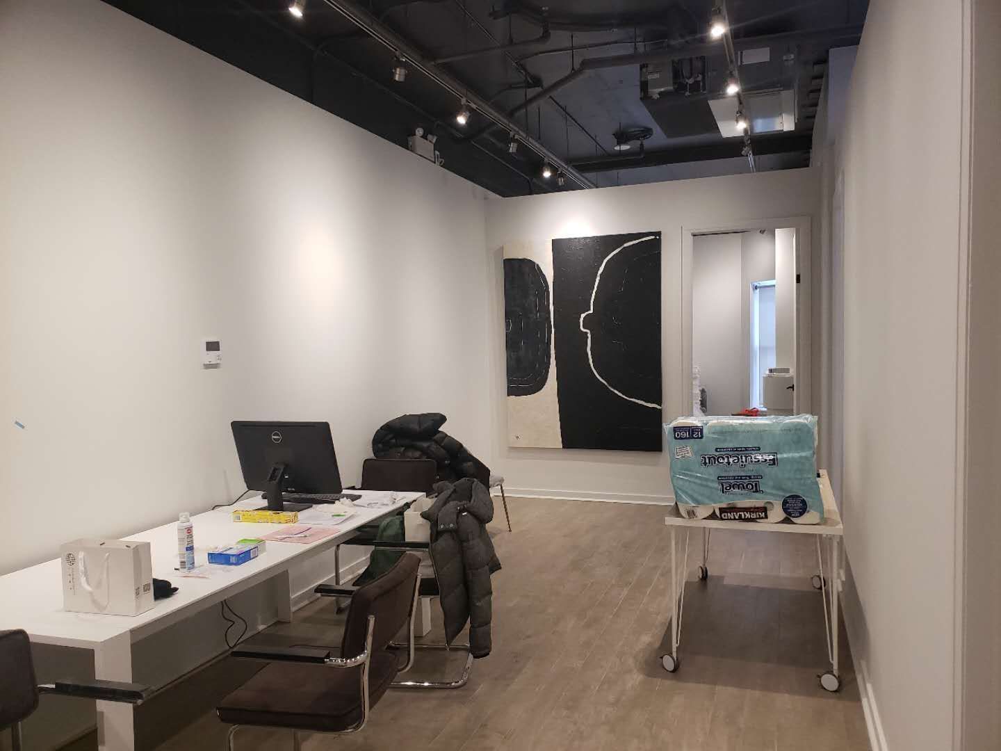 This image highlights the reception and consultation area of a modern beauty and massage spa, completed by a professional Toronto renovation company specializing in commercial interior renovations. The space features clean wall finishes, wood-look flooring, and an open ceiling concept with track lighting to create a contemporary and welcoming environment. Functional workspace planning allows for efficient client check-in, consultation, and daily operations. The minimalist layout and neutral tones enhance the overall calm and professional atmosphere, making it ideal for spa, wellness, and beauty clinic interiors across Toronto and the GTA.