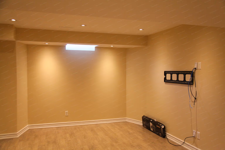 This image showcases a completed basement renovation project in Markham, featuring a clean and functional open living space. The basement includes smooth finished ceilings with recessed lighting, neutral wall tones, durable flooring, and a prepared media wall setup. Designed to enhance comfort, lighting quality, and everyday usability, this basement renovation reflects modern residential renovation standards by a professional Toronto renovation company.