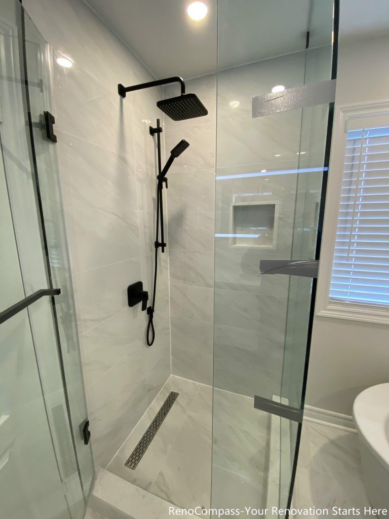 This Markham bathroom renovation focuses on the interior details of the walk-in shower, featuring matte black shower fixtures, a handheld shower set, and a linear floor drain. Full-height marble-look tiles and a recessed wall niche enhance both durability and daily usability, while the clean layout keeps the shower area visually uncluttered and easy to maintain.
City: Markham · Toronto contractor: Reno Compass