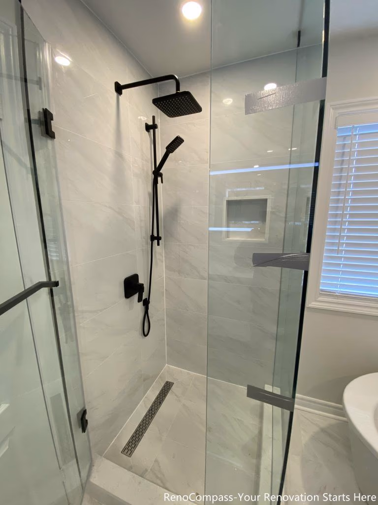 This Markham bathroom renovation focuses on the interior details of the walk-in shower, featuring matte black shower fixtures, a handheld shower set, and a linear floor drain. Full-height marble-look tiles and a recessed wall niche enhance both durability and daily usability, while the clean layout keeps the shower area visually uncluttered and easy to maintain.
City: Markham · Toronto contractor: Reno Compass