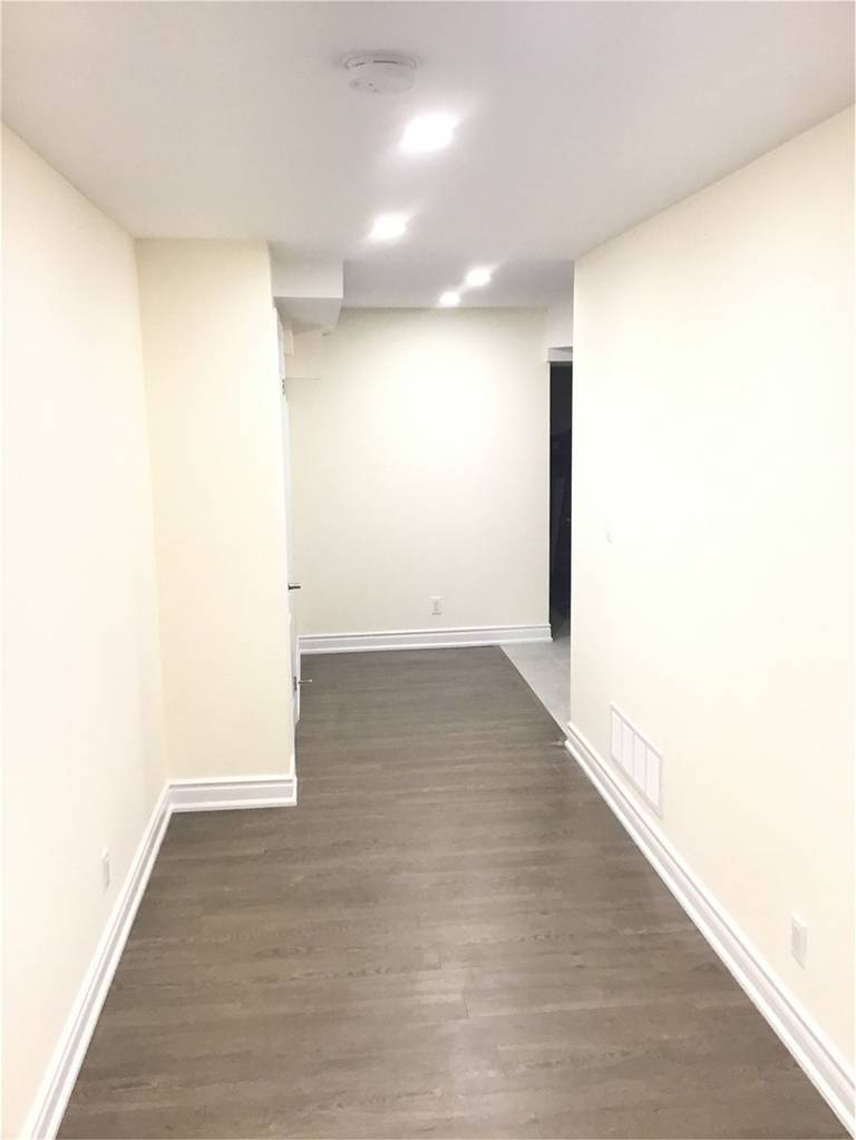 This Mississauga basement renovation features a clean hallway layout with engineered wood flooring, recessed pot lights, and neutral wall finishes that create a bright and welcoming atmosphere. Completed by a trusted Toronto Renovation Company, the design improves flow and functionality while maintaining a modern and cohesive look throughout the finished basement living space.