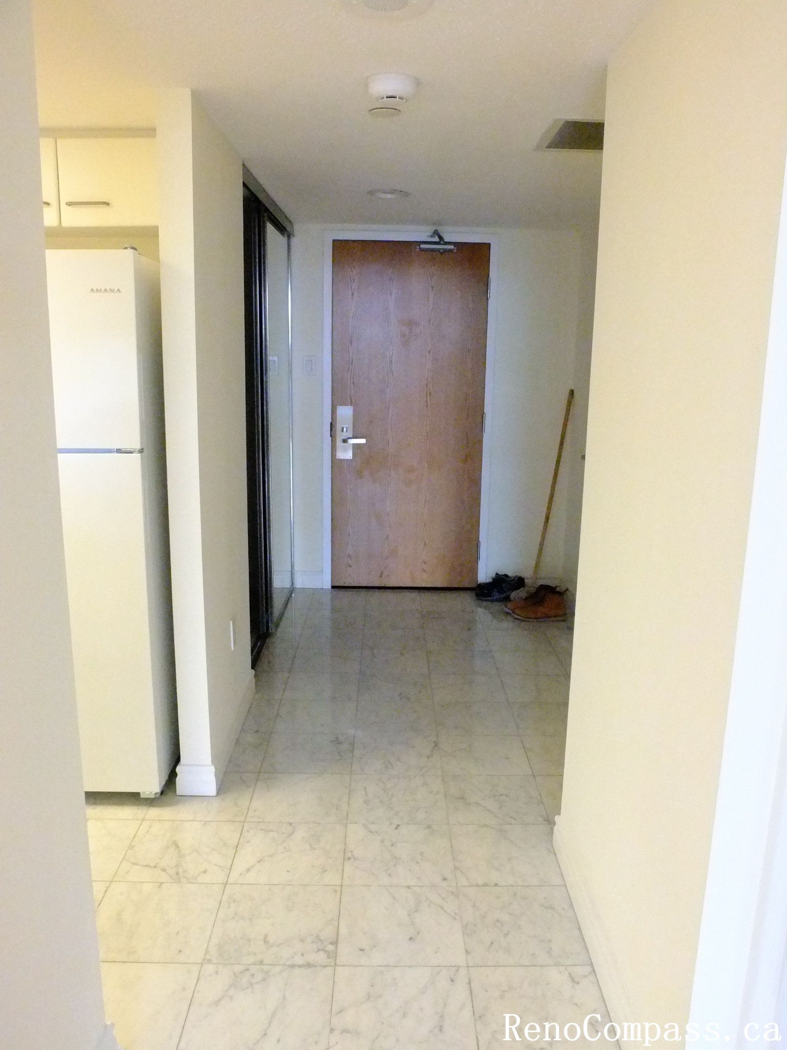 This image shows the original entry hallway of a Toronto condominium before renovation. The space features tiled flooring, a main entrance door, and access to the kitchen and living areas. As part of a Toronto interior renovation project, the hallway layout and finishes were prepared for upgrades to improve functionality, lighting, and overall modern interior design.