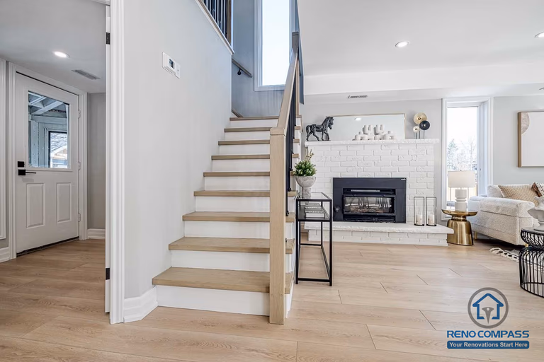 This Georgian interior renovation features a refined staircase design with light wood treads, clean railings, and a clear view toward the living room fireplace. The layout balances classic structure with modern finishes, completed by a Toronto renovation company.
