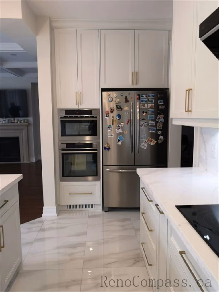This Aurora kitchen renovation features custom white shaker cabinets with built-in oven and refrigerator layout, quartz countertops, and elegant brushed gold hardware. The spacious design improves workflow and storage while maintaining a clean and modern aesthetic. Completed by a professional Toronto renovation company focused on functional kitchen planning, high-quality finishes, and timeless interior design.
