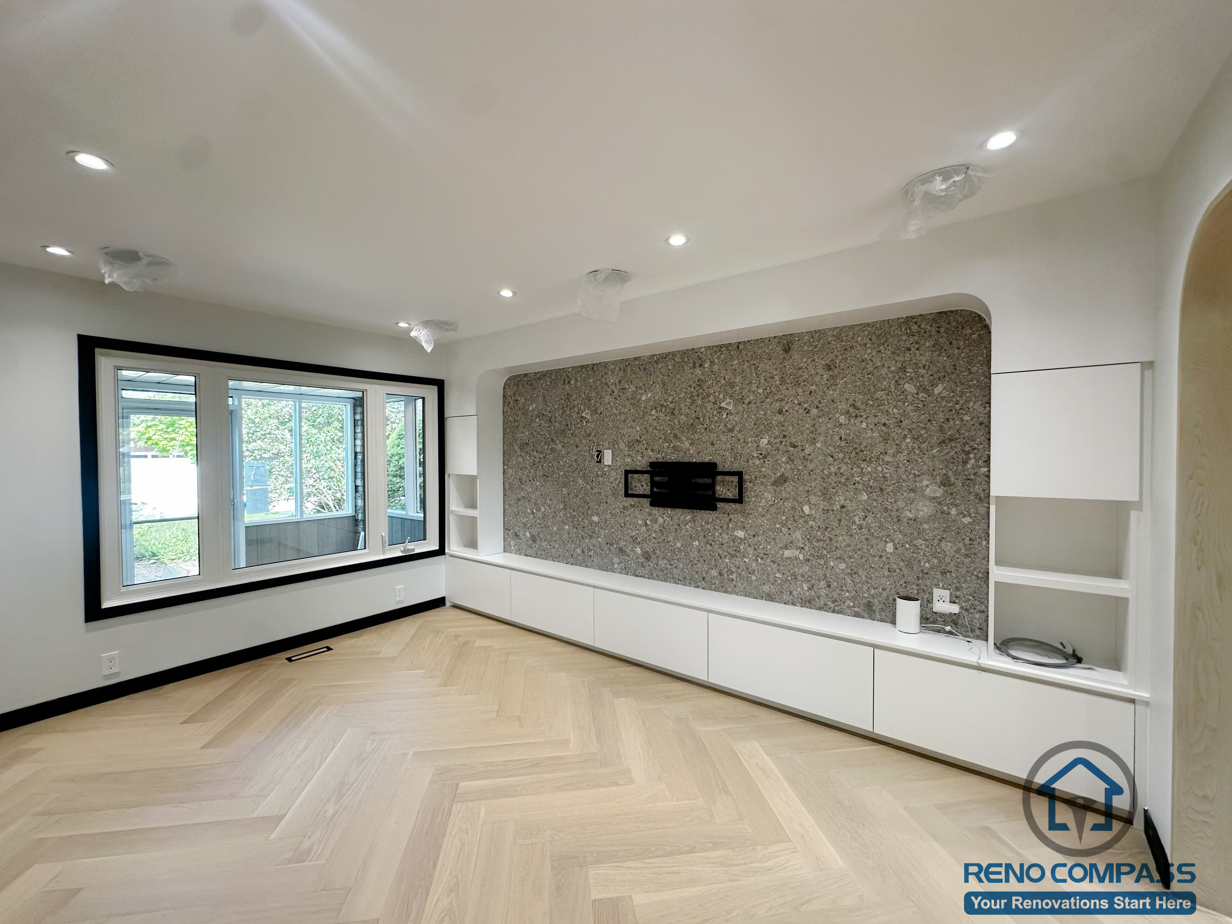 This renovated living room in Richmond Hill features a bright, modern aesthetic with custom-built storage and a seamless TV wall design.
The large picture windows bring in abundant natural light, highlighting the light herringbone flooring and the curved architectural detailing around the feature wall.

The built-in media cabinet provides generous storage while keeping the space clean and uncluttered. Perfect for families looking for a calm, functional, and contemporary living environment.

Key features:

Custom media wall with integrated shelves

Light herringbone engineered flooring

Soft white and stone-textured finishes

Upgraded recessed lighting

Modern Richmond Hill living room renovation