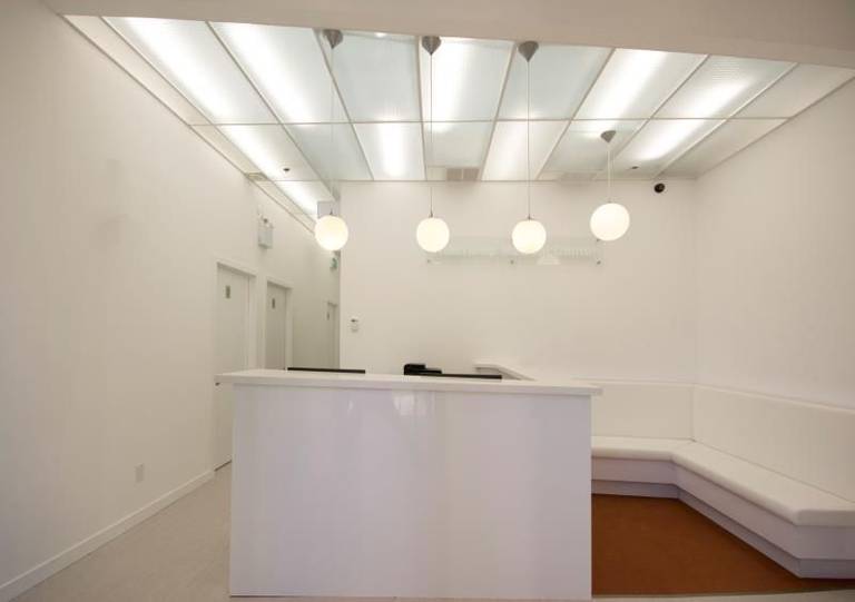 Elegant spa treatment room completed during a Toronto spa commercial renovation. The space features a professional massage bed, decorative frosted glass window panels with floral patterns, soft curtains, and warm pendant lighting designed to create a calm