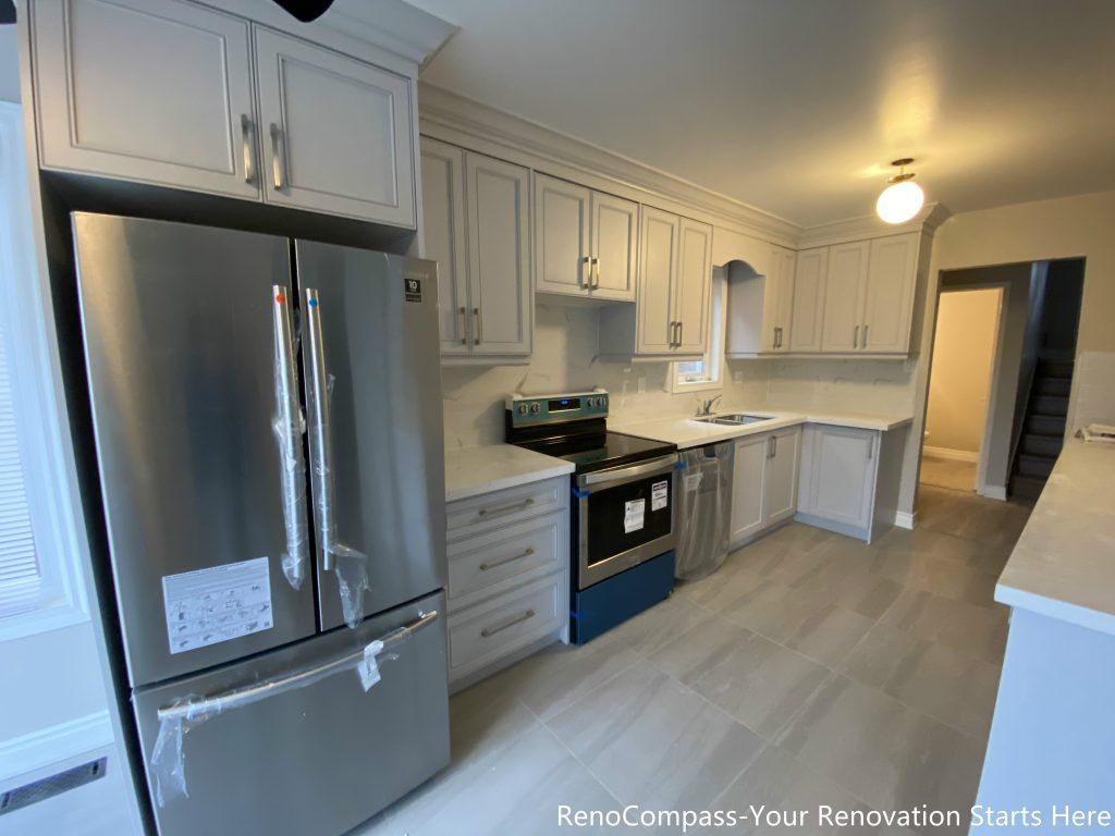 This Mississauga interior renovation features a fully updated kitchen with white shaker-style cabinetry, quartz countertops, and stainless steel appliances. The L-shaped layout maximizes counter space and storage, while full-height upper cabinets enhance organization and visual continuity. Light-toned flooring and neutral finishes create a bright, clean kitchen environment designed for everyday cooking, efficiency, and long-term durability.