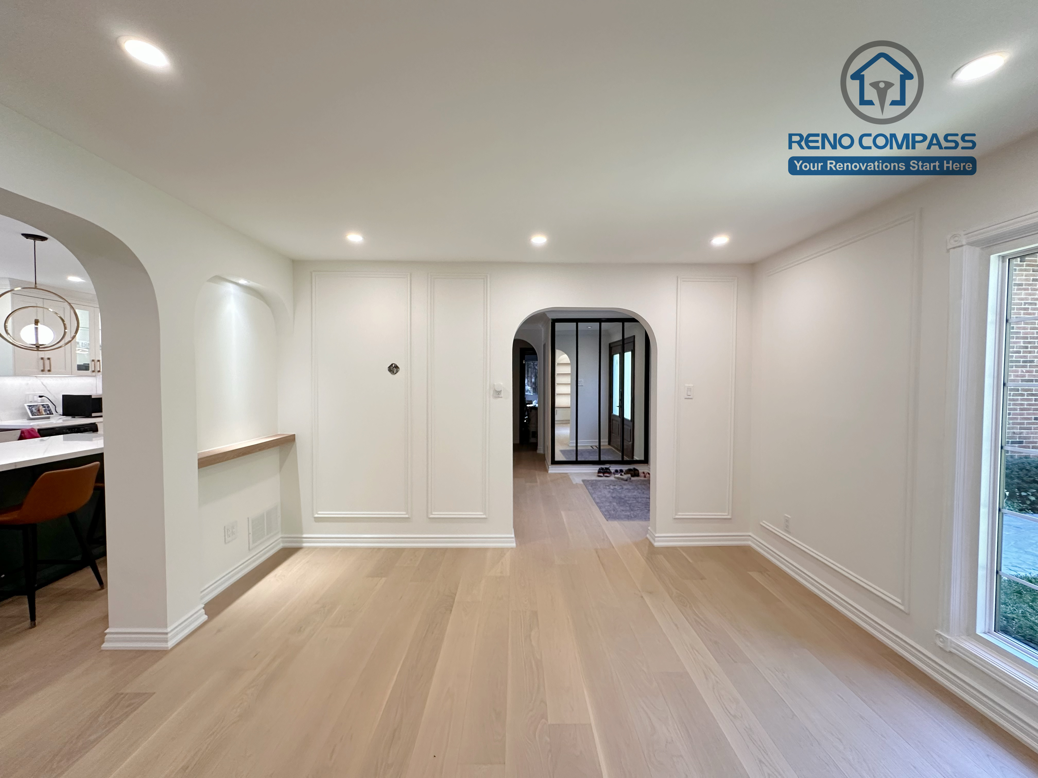 This Markham kitchen renovation extends into a bright open dining area featuring arched openings, wall panel detailing, and wide-plank hardwood flooring. The layout creates a smooth transition between kitchen and living spaces, enhancing flow and natural light. Completed by a professional Toronto renovation company, Reno Compass Inc., the design emphasizes proportion, openness, and cohesive interior planning.