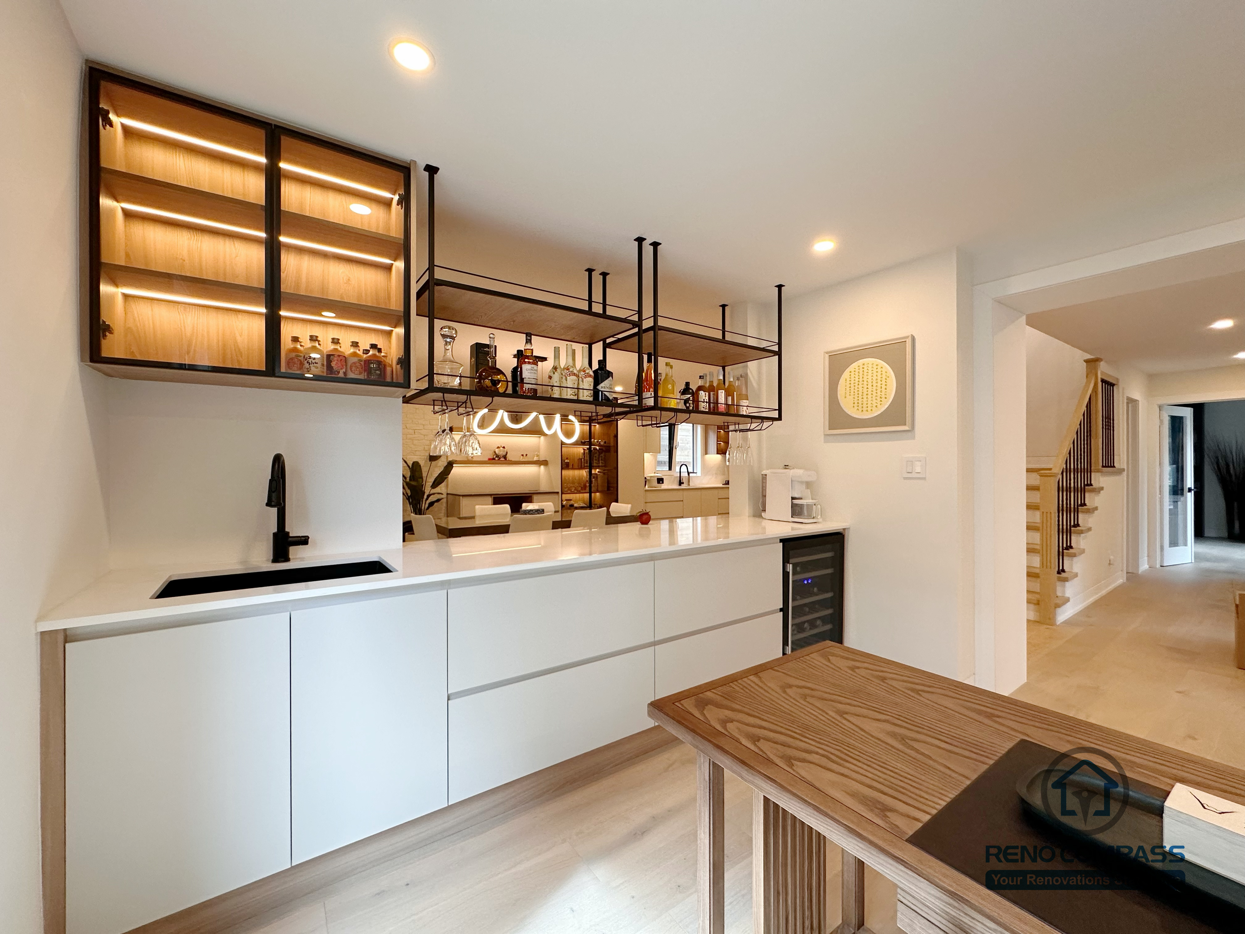 A custom kitchen bar and beverage station in Toronto featuring built-in cabinetry, glass display cabinets with LED lighting, and an integrated sink. This tailored cabinetry design enhances entertaining functionality while maintaining a sleek, modern look, completed by a professional Toronto renovation company.