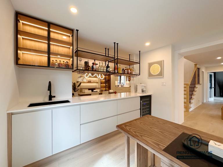 A custom kitchen bar and beverage station in Toronto featuring built-in cabinetry, glass display cabinets with LED lighting, and an integrated sink. This tailored cabinetry design enhances entertaining functionality while maintaining a sleek, modern look, completed by a professional Toronto renovation company.