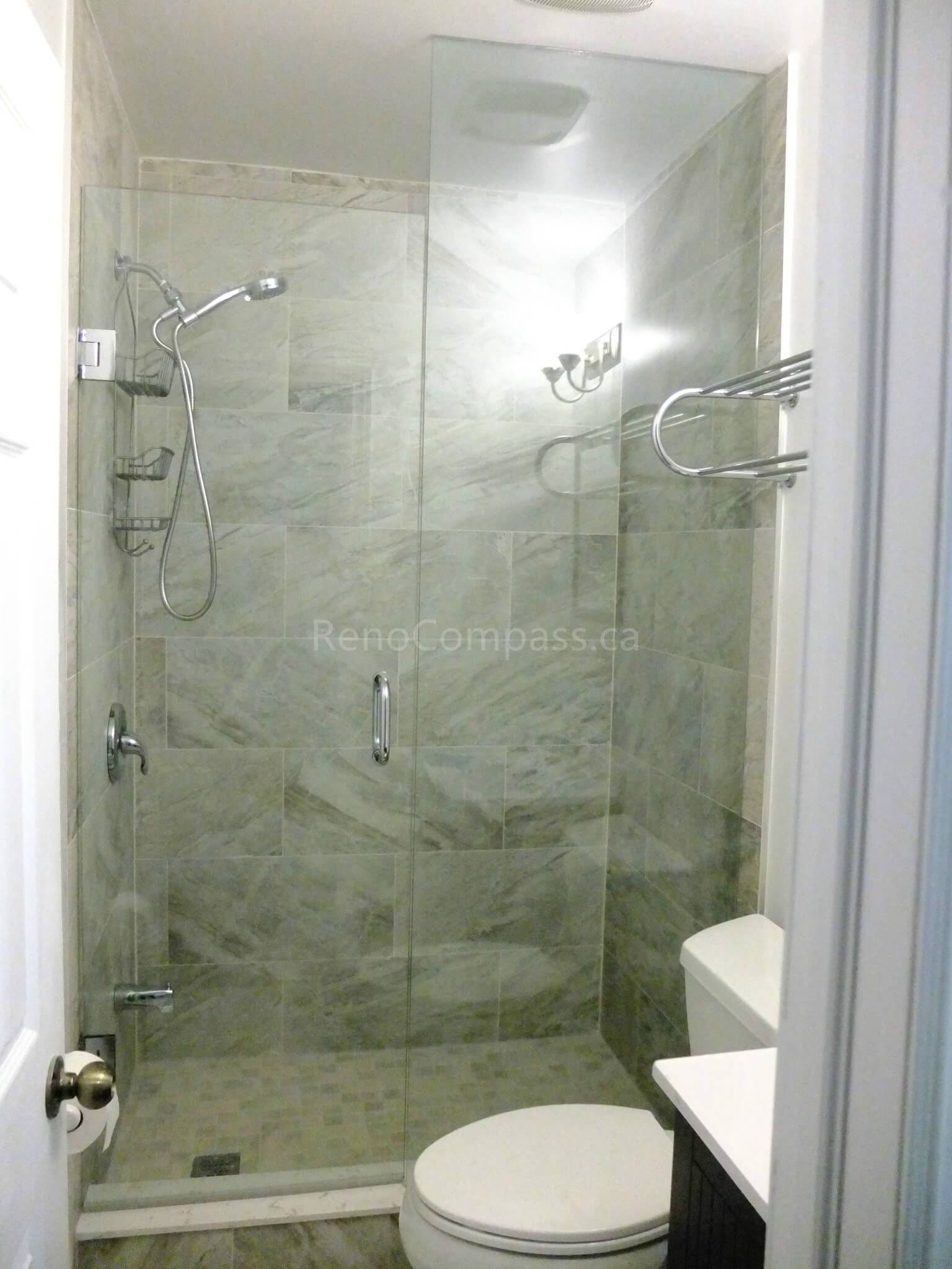 This image showcases a completed bathroom upgrade as part of a North York interior renovation project. The design features a frameless glass shower enclosure, full-height marble-look wall tiles, modern chrome fixtures, and a clean, space-efficient layout. The renovation enhances both functionality and visual openness, creating a bright, modern bathroom suitable for compact urban homes. Completed by a professional Toronto renovation company with a focus on quality workmanship and practical design.