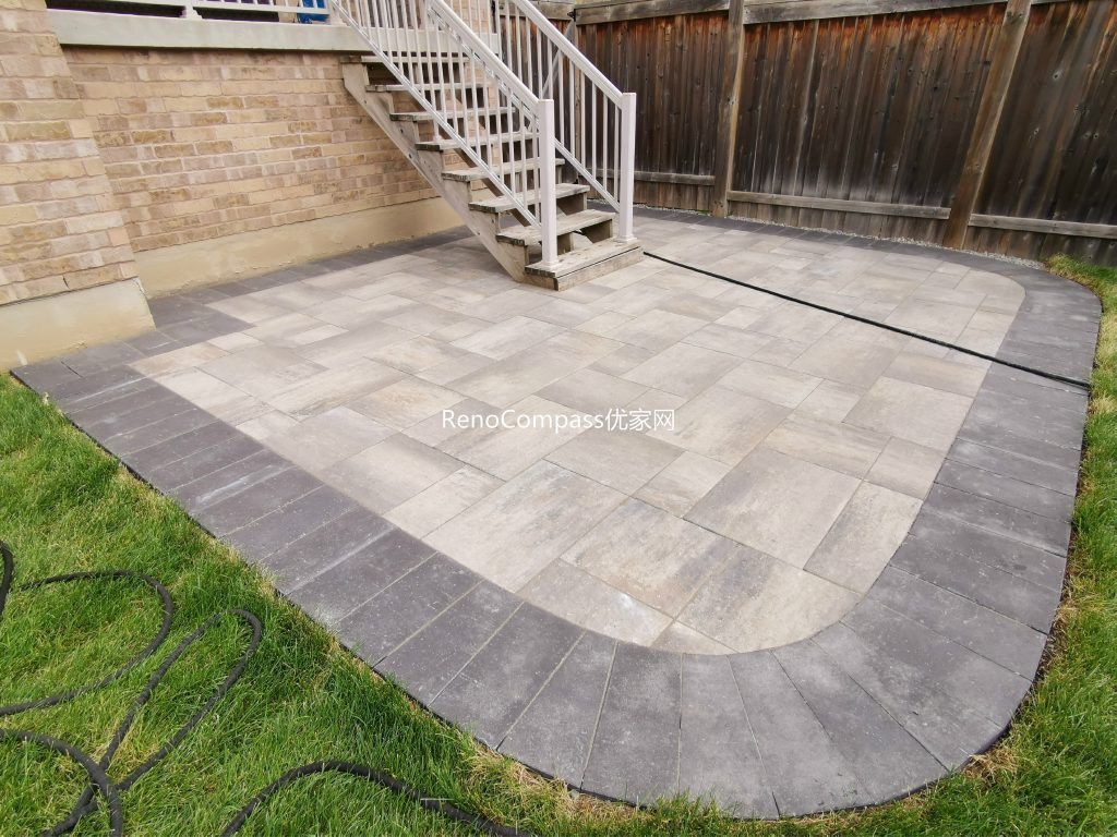 A stunning backyard interlocking patio in Vaughan featuring a defined dark border and seamless transition to the lawn area. Designed and installed by Reno Compass, this elegant stone layout provides a durable and stylish space for outdoor living.