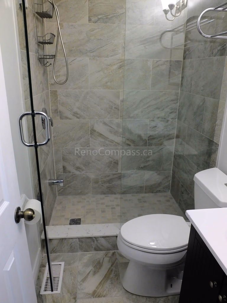 This North York bathroom renovation showcases a modern walk-in glass shower with full-height marble-look tile walls, upgraded fixtures, and a clean space-saving layout. Completed by a professional Toronto renovation company, the project focuses on maximizing functionality, improving lighting, and creating a bright, elegant bathroom with durable materials and precise finishing details.