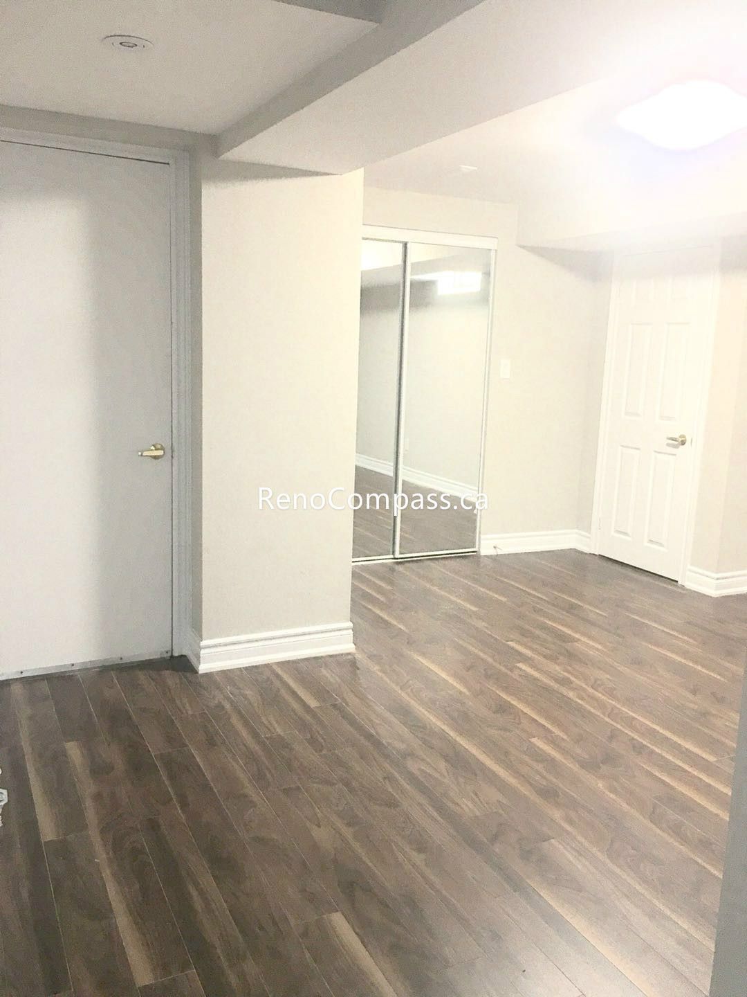 This Toronto basement renovation showcases a newly finished basement room with durable wood flooring, smooth neutral walls, and modern sliding closet doors for practical storage. The upgraded layout offers a bright and versatile space suitable for a bedroom, home office, or family living area. Completed by an experienced Toronto renovation company, the project highlights clean finishes, functional design, and quality craftsmanship for a comfortable and modern basement living environment.