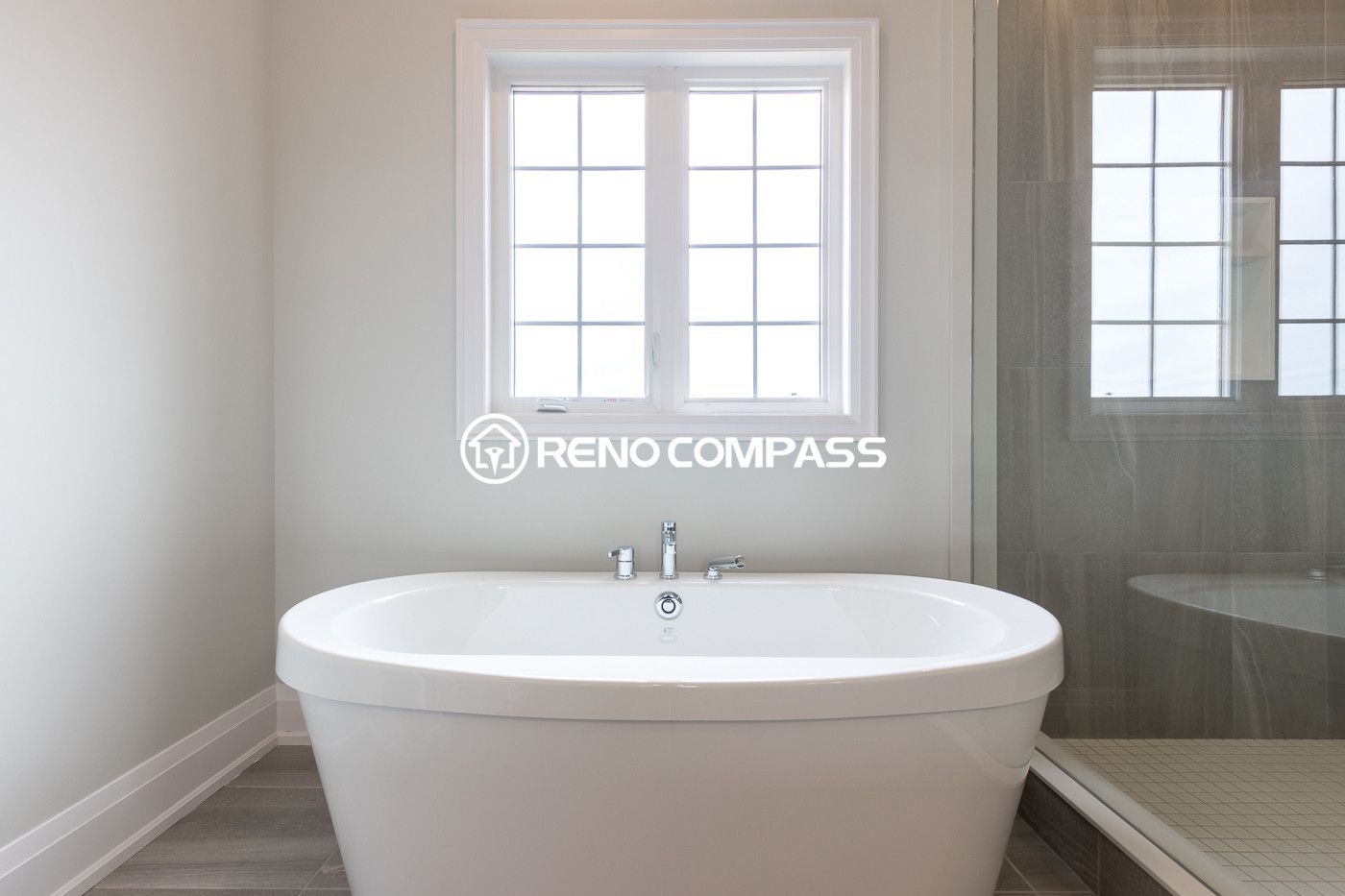 Elegant bathroom renovation in Newmarket featuring a modern freestanding bathtub, large window for natural light and a glass shower enclosure. Completed by a professional Toronto renovation company, this bathroom design creates a relaxing and luxurious spa-like atmosphere for the homeowner.