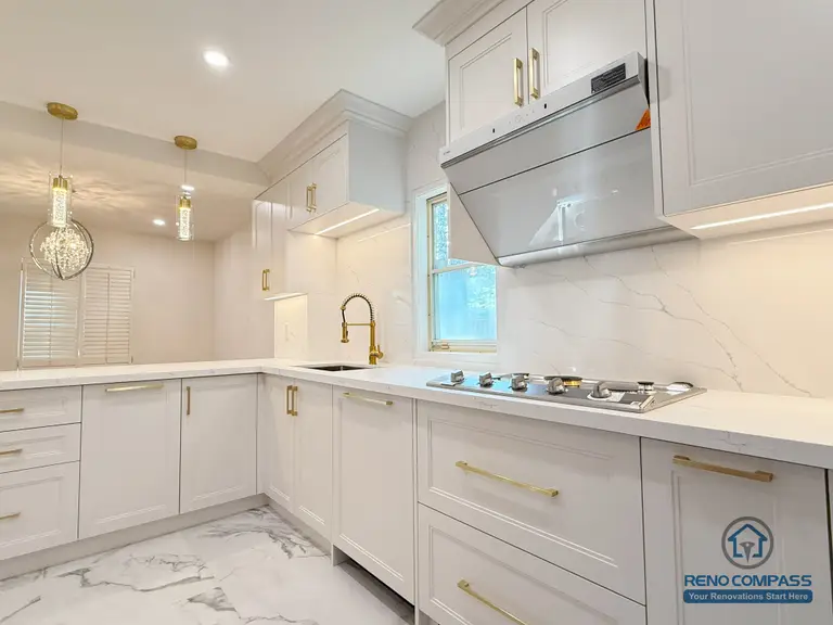 This North York kitchen renovation features a modern white-and-gold palette with a clean U-shaped layout.
The extended countertop provides efficient workflow and ample storage, while the marble-style backsplash and flooring elevate the space with a premium, elegant feel.

Project by: Reno Compass Inc.
这套北约克厨房以白色橱柜搭配金色五金，打造明亮高级的现代空间。
U 型操作台延伸出更顺畅的动线，满足日常烹饪与多人同时使用需求。
大理石纹理背板与瓷砖地面提升整体质感，高效、美观、实用兼具。

施工单位：Reno Compass Inc.