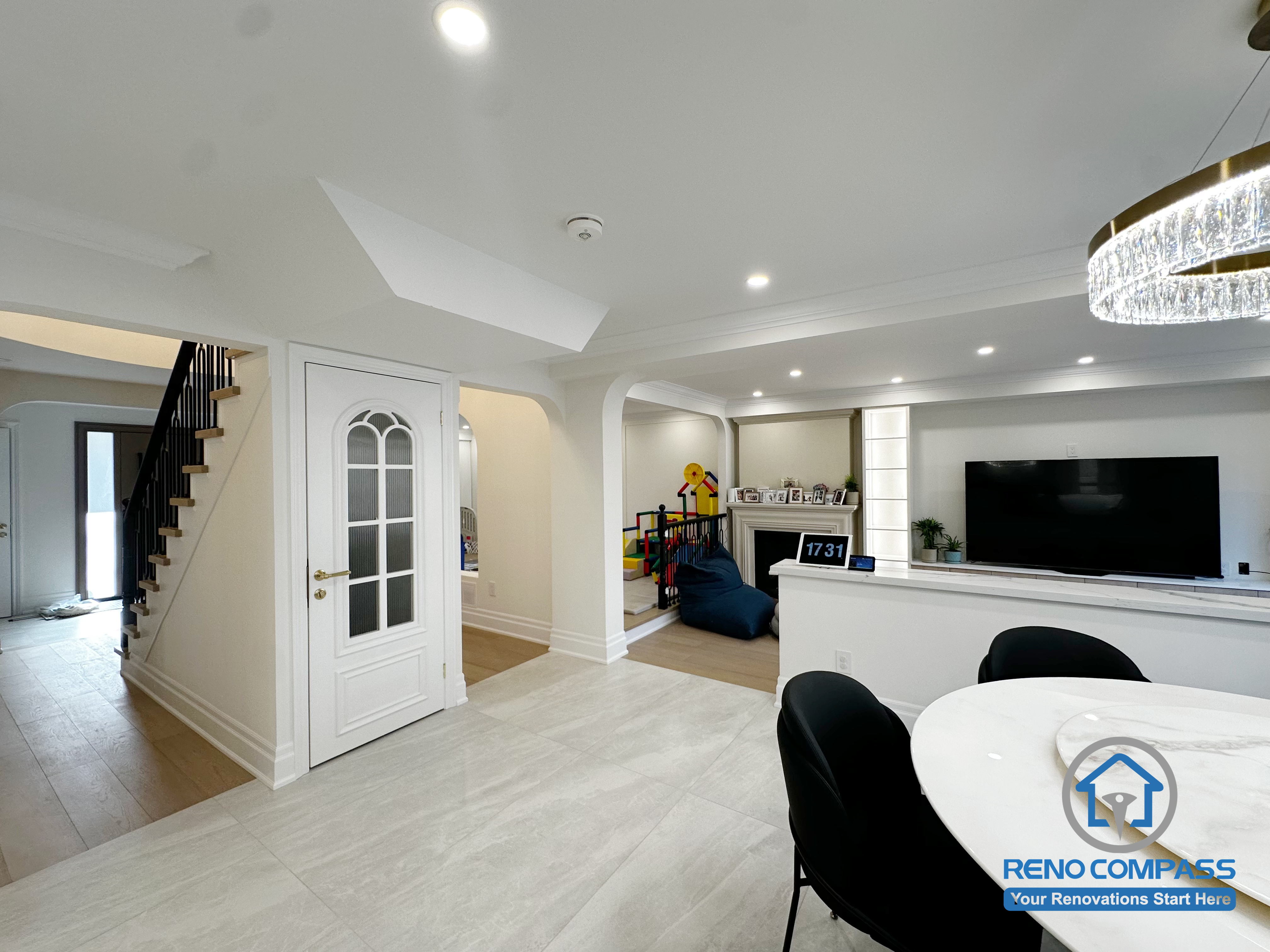 This image highlights the open dining area within the Markham interior renovation, where architectural arches are used to define space without closing off sightlines. The layout connects the dining zone seamlessly with the staircase, family area, and adjacent living spaces, creating a fluid and practical circulation path. Light-toned flooring, recessed ceiling lighting, and soft curved details contribute to a bright and cohesive atmosphere. The design balances openness and structure, allowing the dining area to function naturally as part of the home’s central gathering space rather than a separate room.