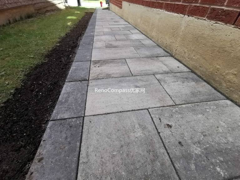 Backyard stone pathway interlocking project located in Richmond Hill. The design incorporates a raised flower bed and smooth stone pavers to create a natural, stylish transition between yard and garden. Professionally completed by Reno Compass for a lasting finish.