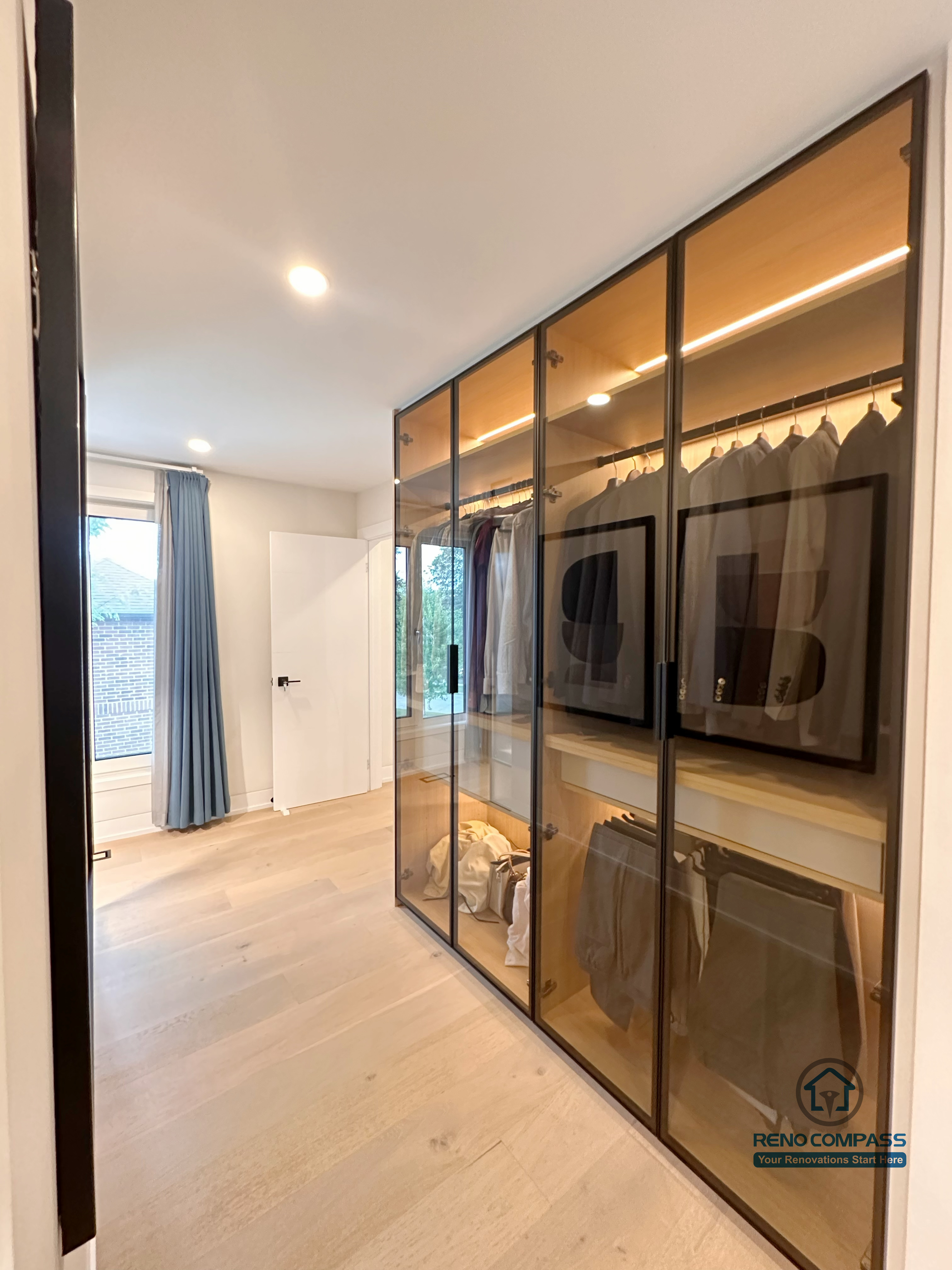 A custom walk-in closet renovation in Toronto featuring floor-to-ceiling glass wardrobe cabinetry with integrated LED lighting. This bespoke storage solution enhances organization and visibility while maintaining a sleek, modern look, completed by a professional Toronto renovation company.