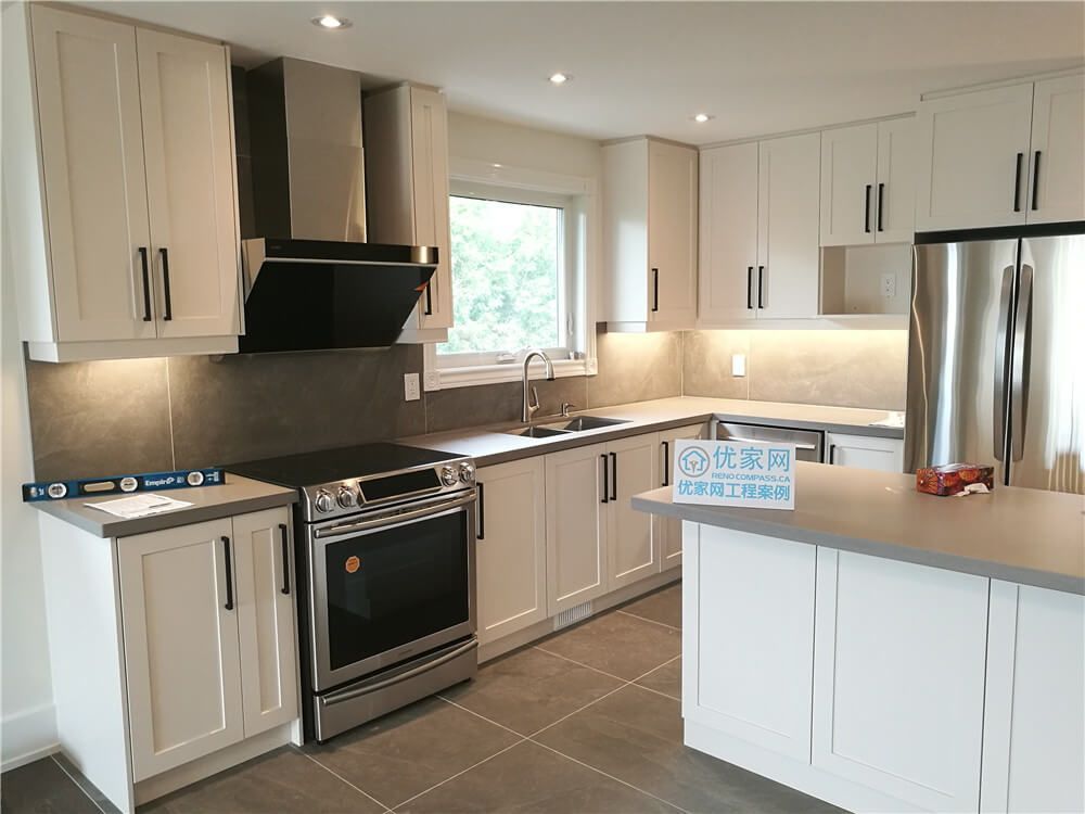 This North York interior renovation highlights an open-concept kitchen featuring a central island, custom white cabinetry, stainless steel appliances, and recessed ceiling lighting. The layout improves workflow and circulation while maintaining a clean, modern look that connects seamlessly with the surrounding living areas.