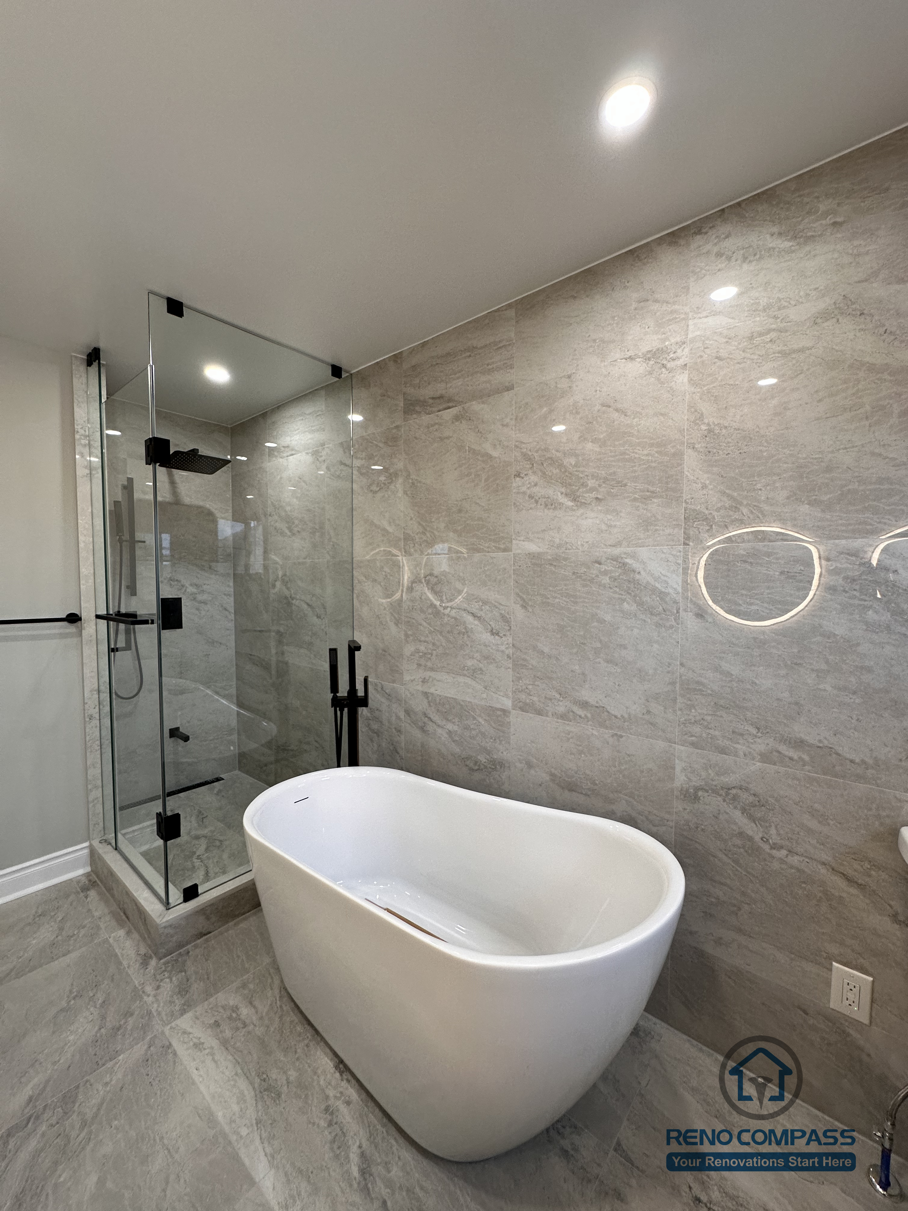 This Markham bathroom renovation features a modern layout with a freestanding bathtub, glass-enclosed shower, and large-format stone-look tiles. Designed and built by a professional Toronto renovation company, Reno Compass Inc., the space balances functionality, clean lines, and long-term durability.