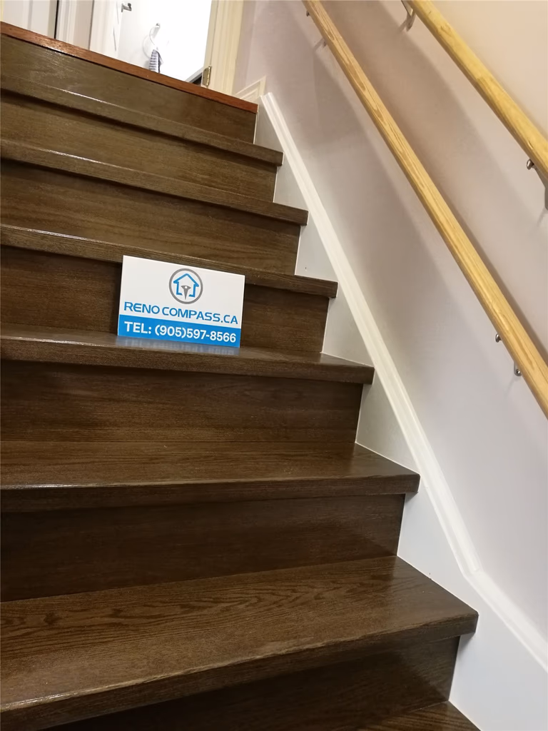 This image features a finished basement staircase renovation in Markham, showcasing modern wood stairs, matching basement flooring, and clean white railings for a cohesive and safe transition between floors. The upgraded staircase improves both functionality and visual flow, creating a polished connection between the main floor and basement. Completed by a professional Toronto renovation company with attention to detail, safety, and long-term durability.