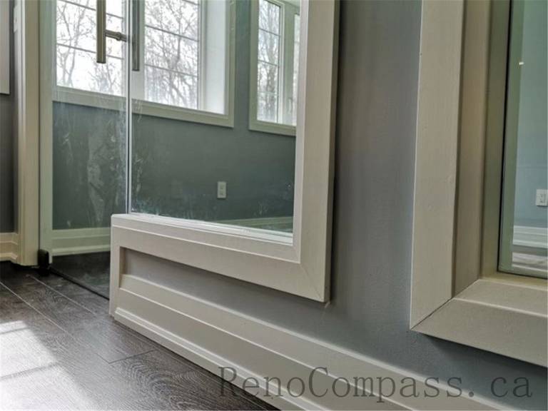 Contemporary basement renovation with a glass partition wall, maximizing natural light and creating an open, seamless flow between spaces. A refined Aurora project designed and built by Reno Compass.
