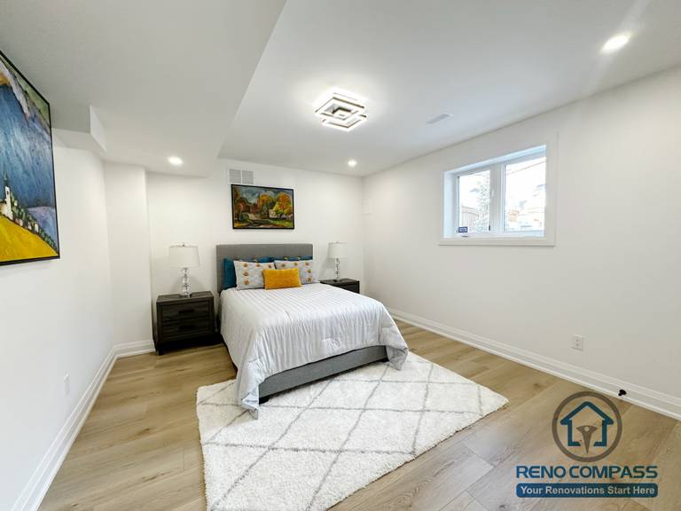 This Richmond Hill basement renovation includes a finished bedroom designed for comfort and everyday use. The space features an egress window that brings in natural light while meeting basement safety requirements. Neutral wall tones, recessed ceiling lighting, and wide-plank flooring help create a bright and balanced atmosphere. The layout comfortably accommodates a full-size bed and bedside furniture, making the room suitable for guests, extended family, or long-term basement living.