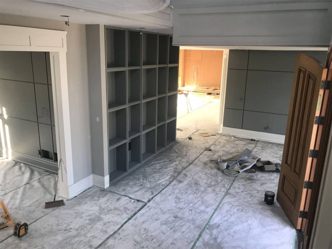 This photo captures an in-progress professional wall painting project in Toronto, featuring detailed floor protection and surface preparation. Custom built-in shelving units and wall panels are carefully prepped for a smooth and even paint finish. Our Toronto painting and renovation team ensures precise workmanship, clean masking, and high-quality interior finishing to deliver modern, durable, and beautifully refreshed living spaces.