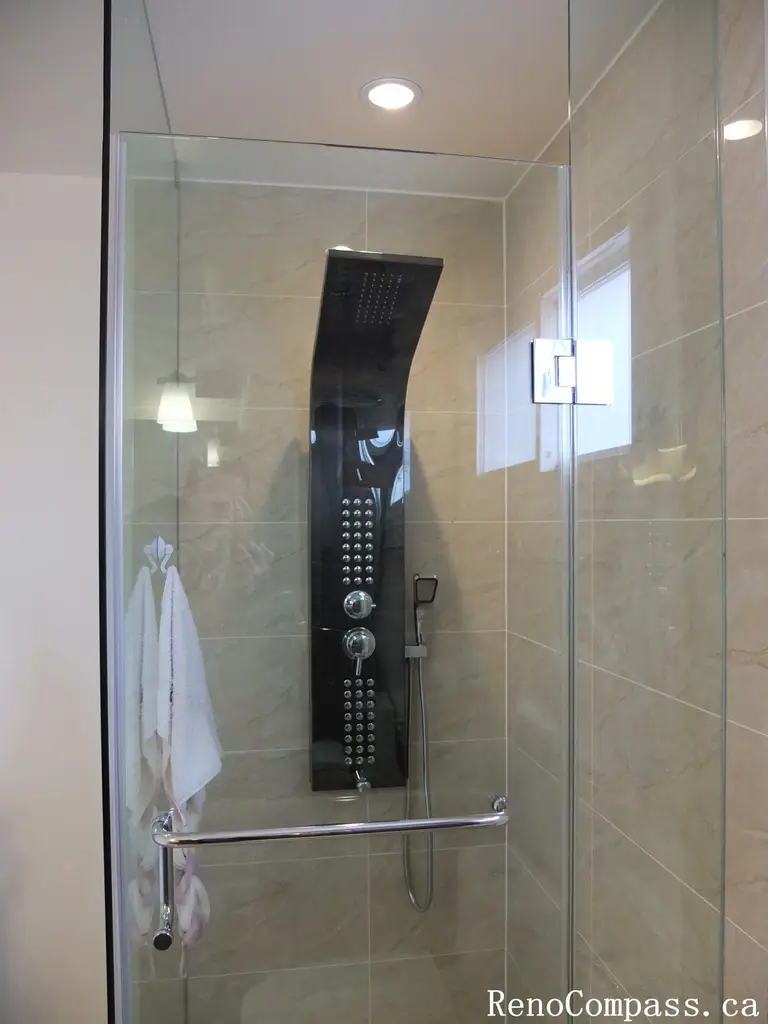 Interior bathroom renovation in North York featuring a frameless glass shower, full-body rain shower system, and large-format porcelain wall tiles. This Toronto interior renovation focuses on modern functionality, clean detailing, and efficient use of space for everyday comfort.