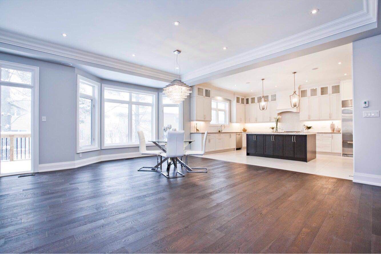 Bright open-concept kitchen and dining area completed as part of a Toronto design build custom build project, featuring a spacious layout with large windows, hardwood flooring, and a modern kitchen island. This whole house renovation Toronto project highlights the seamless connection between cooking, dining, and living spaces, creating a functional and elegant interior commonly found in luxury custom homes across Toronto.