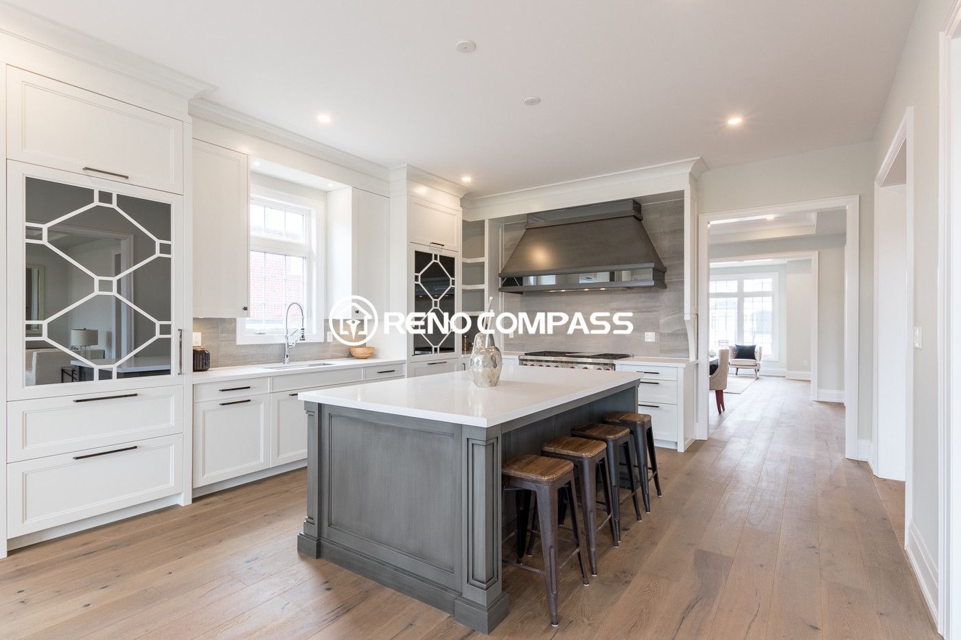 Modern open concept kitchen renovation in Newmarket featuring a large kitchen island, custom cabinetry, recessed pot lights, and engineered hardwood flooring. This bright interior renovation creates a seamless connection between the kitchen, dining, and living space for a spacious and elegant home design.