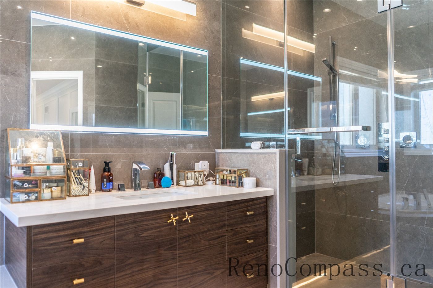 This Richmond Hill bathroom renovation features a custom wood vanity, quartz countertop, LED mirror lighting, and a frameless glass shower with modern fixtures. The clean layout and premium finishes create a spa-like atmosphere while enhancing functionality, showcasing the craftsmanship of a trusted Toronto renovation company specializing in complete home interior renovations.