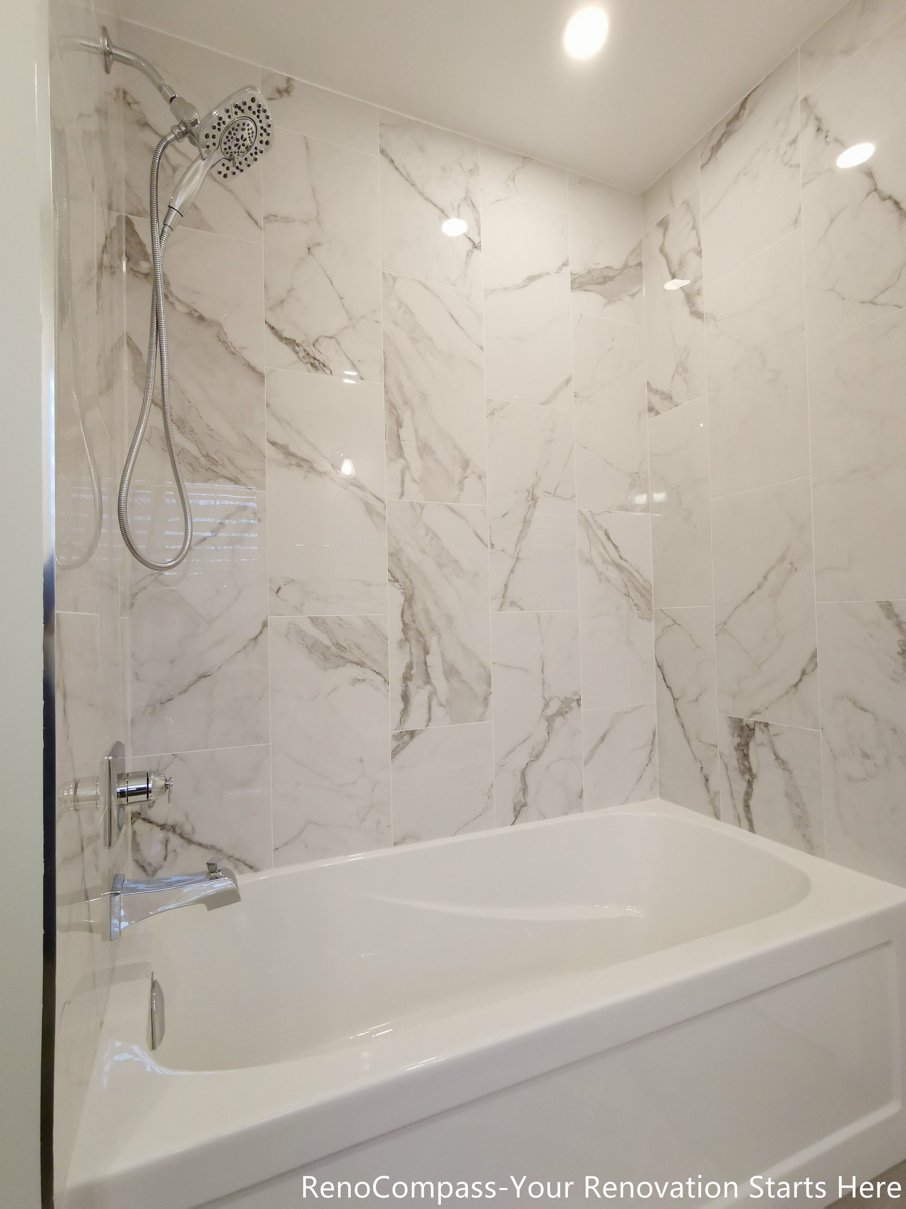This image highlights the bathtub and shower area in an Oakville bathroom renovation, featuring full-height marble-look wall panels that create a clean and seamless backdrop. The integrated bathtub is paired with a wall-mounted shower system, balancing everyday practicality with a spa-inspired aesthetic. Recessed ceiling lighting enhances the natural veining of the stone surfaces, giving the space a bright, refined, and timeless finish.