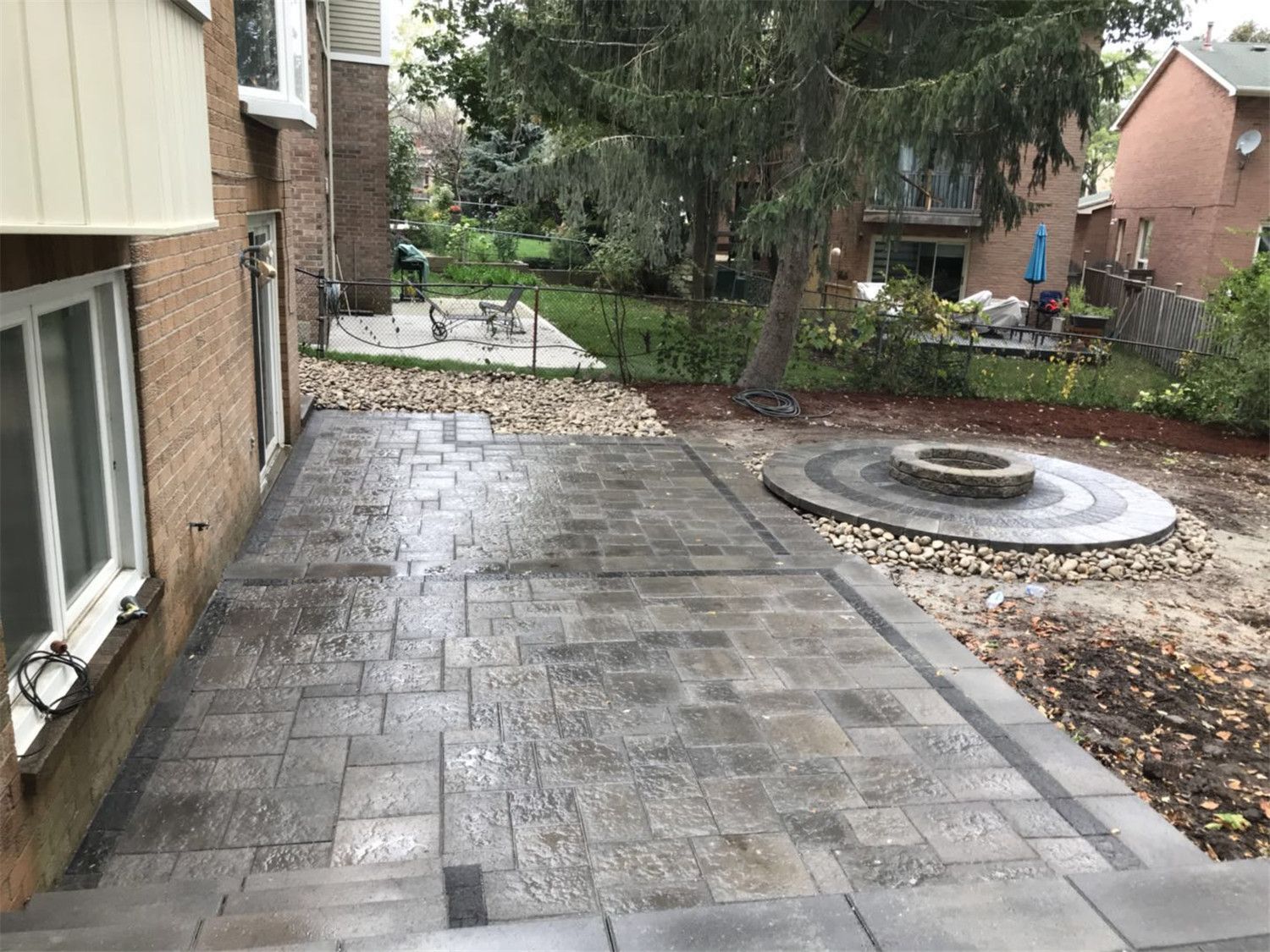 Toronto landscaping renovation featuring a spacious backyard interlock patio designed for outdoor living and entertaining. The durable paving stones, clean edges, and elevated step design create a modern and low-maintenance outdoor space that enhances both functionality and landscape aesthetics for a Toronto residential property.
