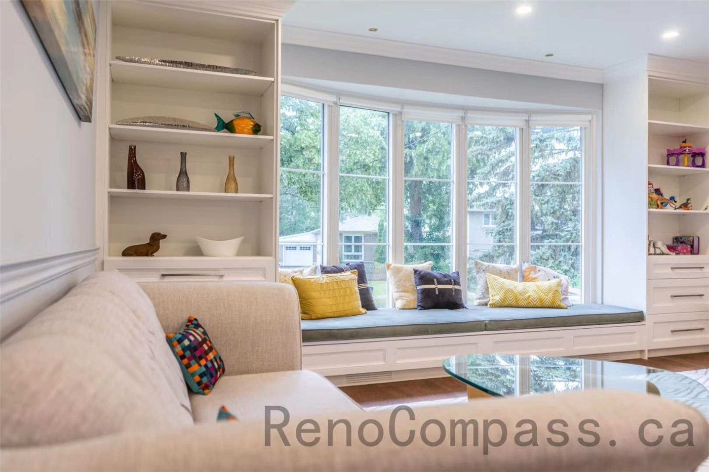 This North York interior renovation features a bright and elegant living space with custom built-in shelving and a beautifully designed bay window bench. The built-in seating area creates a cozy reading nook while maximizing natural light and storage. Paired with soft neutral tones, recessed lighting, and modern furnishings, the room offers both comfort and functionality. Completed by a professional Toronto renovation company, this project showcases thoughtful craftsmanship and timeless interior design that enhances everyday living.