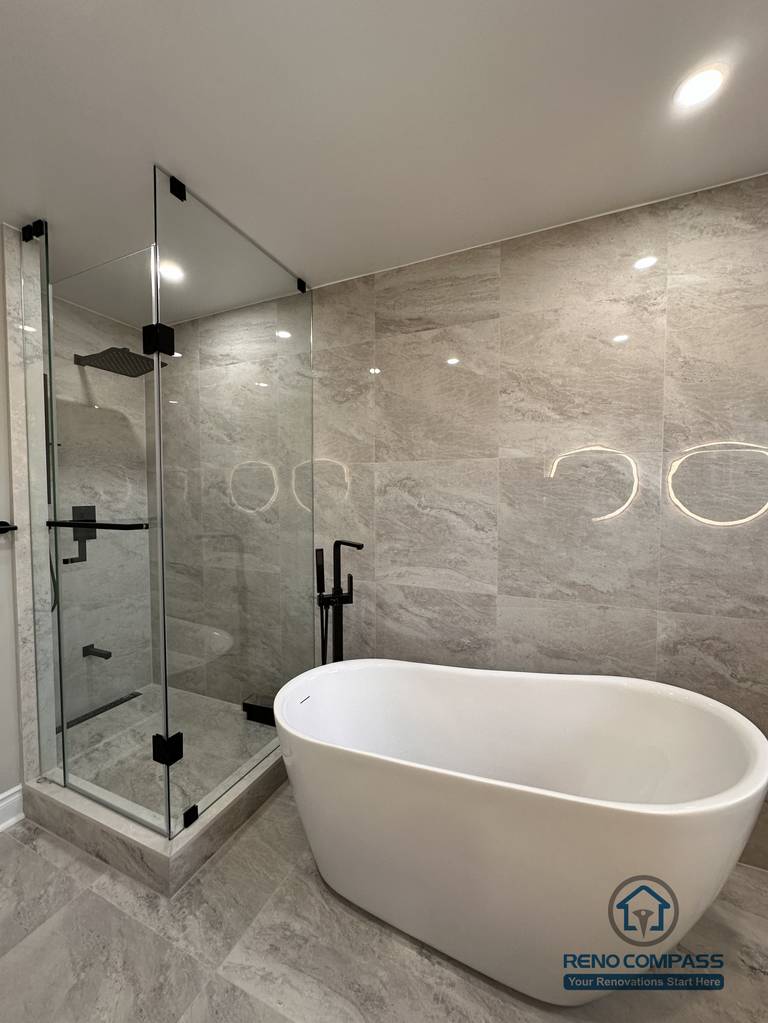 This Markham bathroom renovation features a modern layout with a freestanding bathtub, glass-enclosed shower, and large-format stone-look tiles. Designed and built by a professional Toronto renovation company, Reno Compass Inc., the space balances functionality, clean lines, and long-term durability.