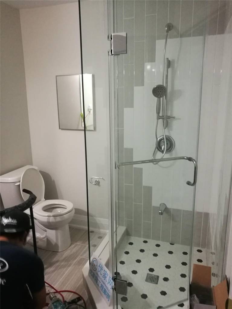 This Markham basement bathroom renovation showcases a modern frameless glass shower enclosure with updated fixtures, new floor tiles, and a refreshed toilet area. Completed by Reno Compass Inc., the upgrade enhances functionality, durability, and a clean contemporary look for the basement living space.