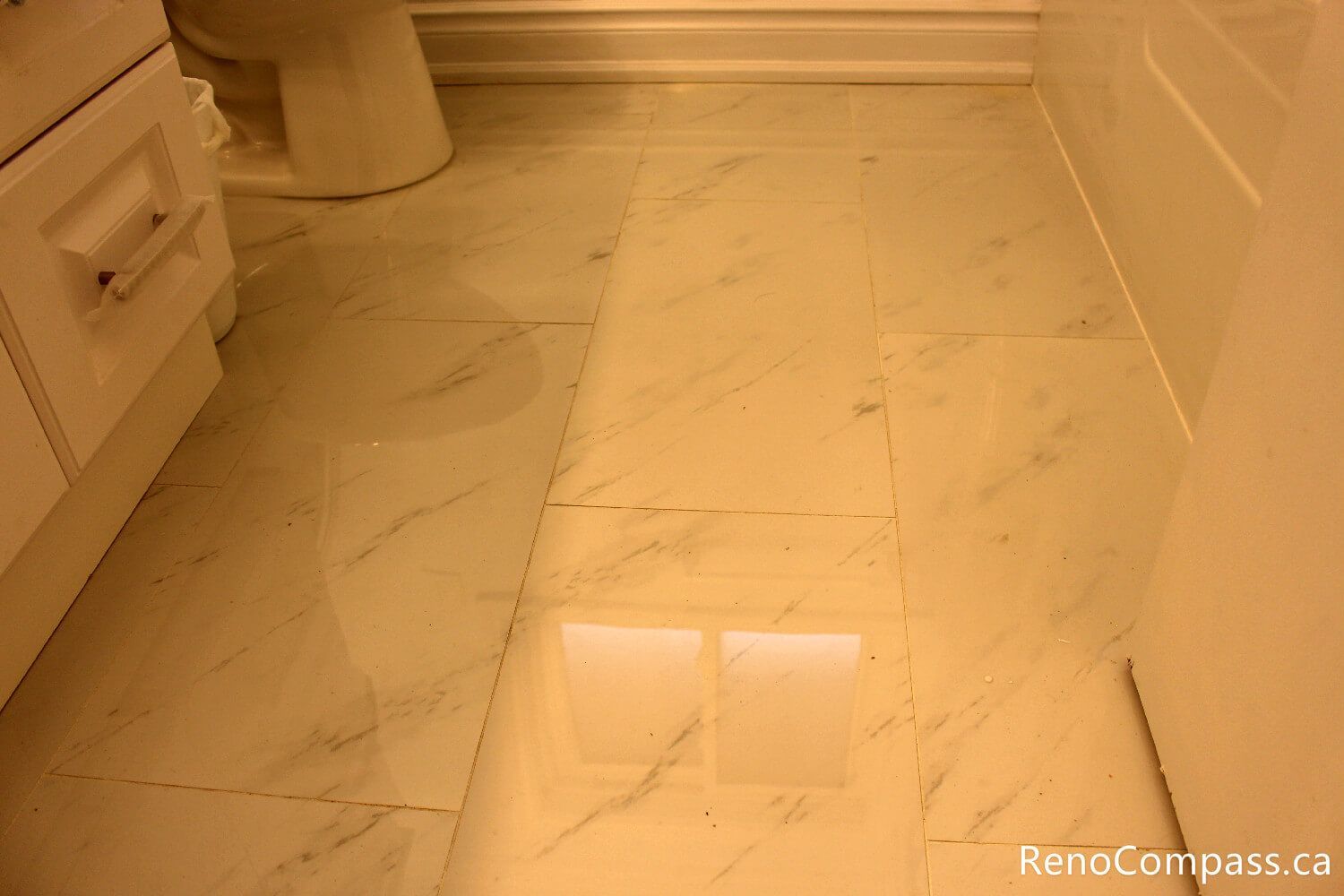 Elegant large-format marble-look porcelain floor tiles installed in a modern Oshawa bathroom renovation. High-gloss, waterproof flooring solution by RenoCompass.ca, designed for durability and a high-end luxury feel in compact spaces.