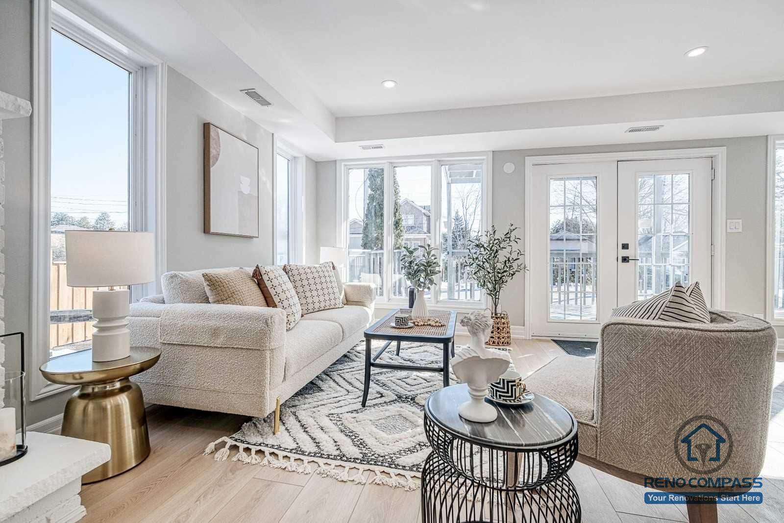 This Georgian interior renovation features a bright living room with large windows, classic fireplace, elegant staircase railing, and light wood flooring. A refined and timeless interior completed by a professional Toronto renovation company.